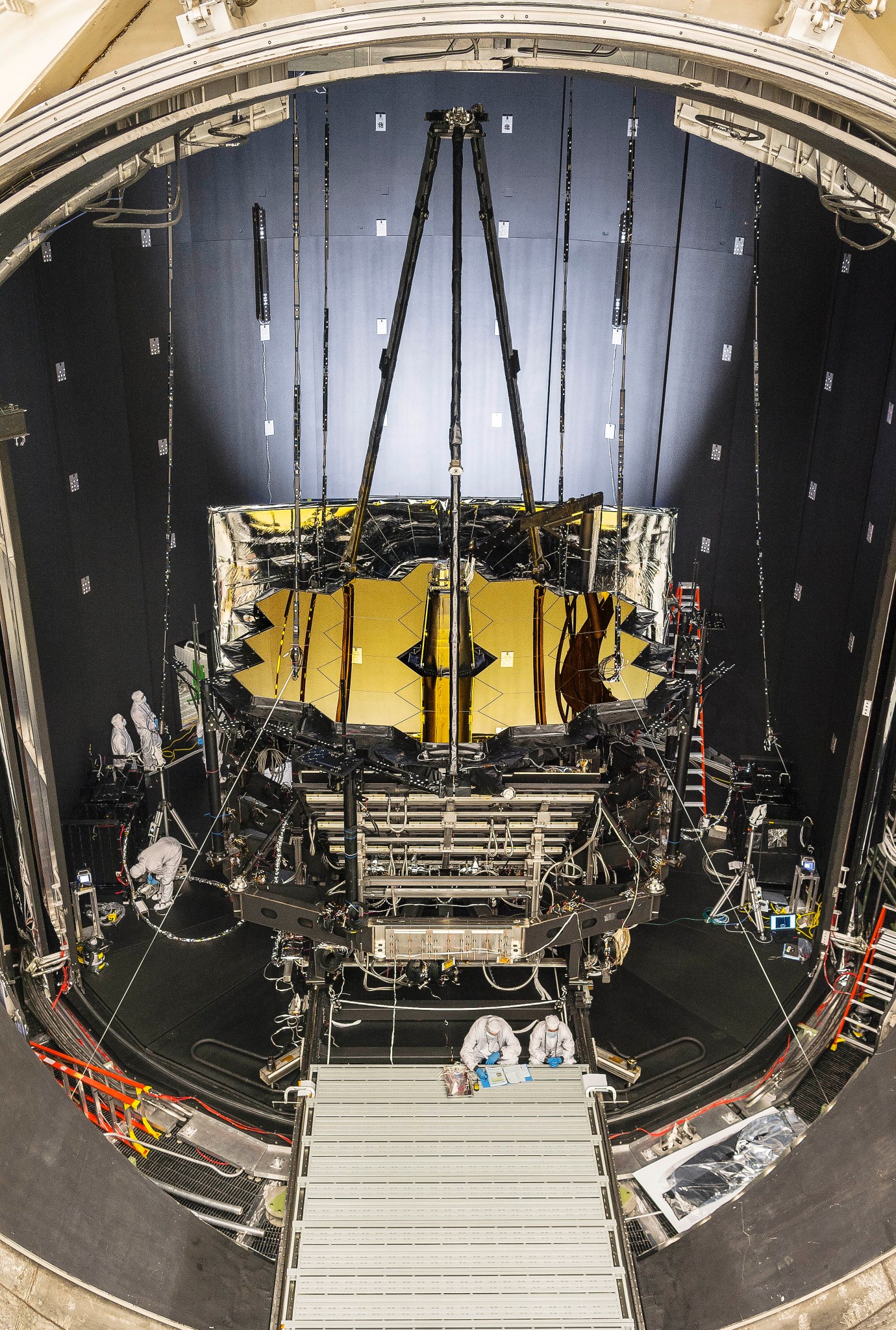 View from above of the Webb telescope's primary and secondary mirror structures in a round chamber with a big circular door.