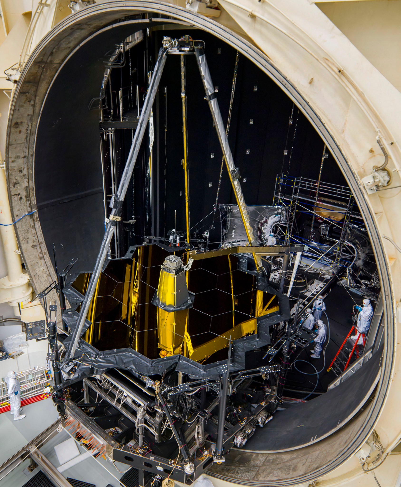 Webb's primary and secondary mirror structures moving into the circular door of a giant round chamber.