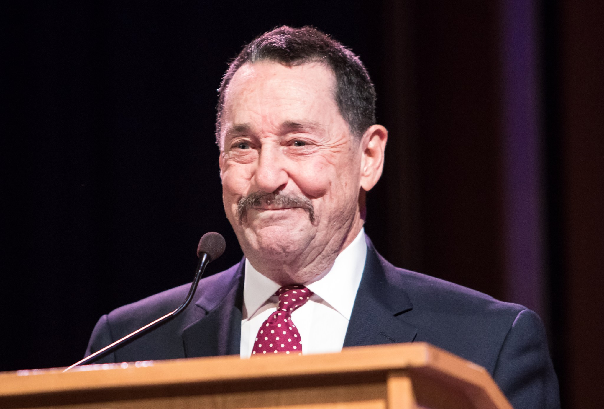 Close-up photo of Peter Cullen as he speaks to students behind a lectern.