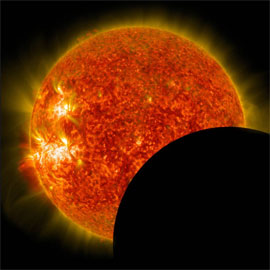 The dark disk of the moon covers the lower-right portion of the sun during a solar eclipse