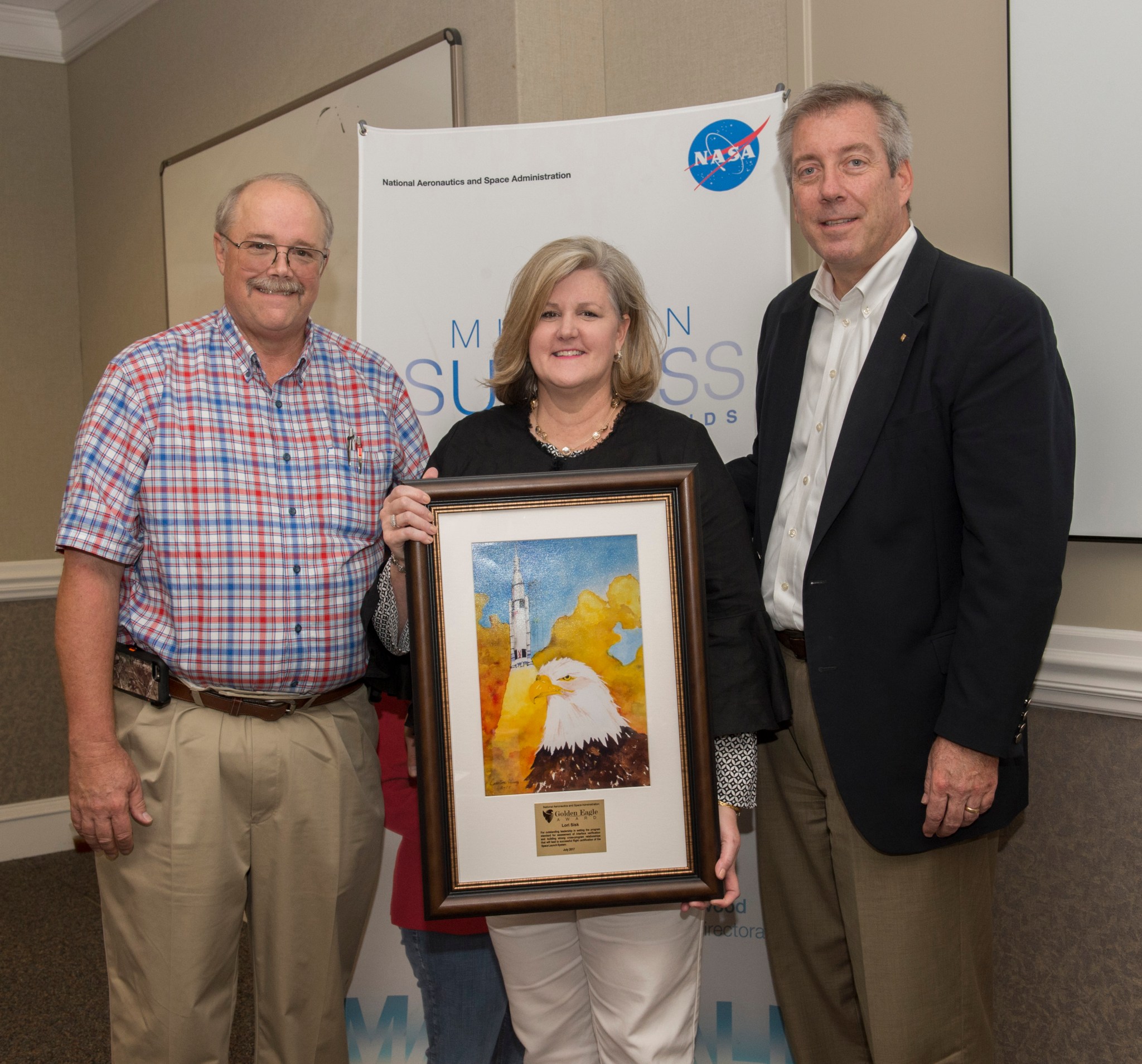 Lori Sisk, center, receives the Golden Eagle award from Rick Burt, left, and Jeff Haars.