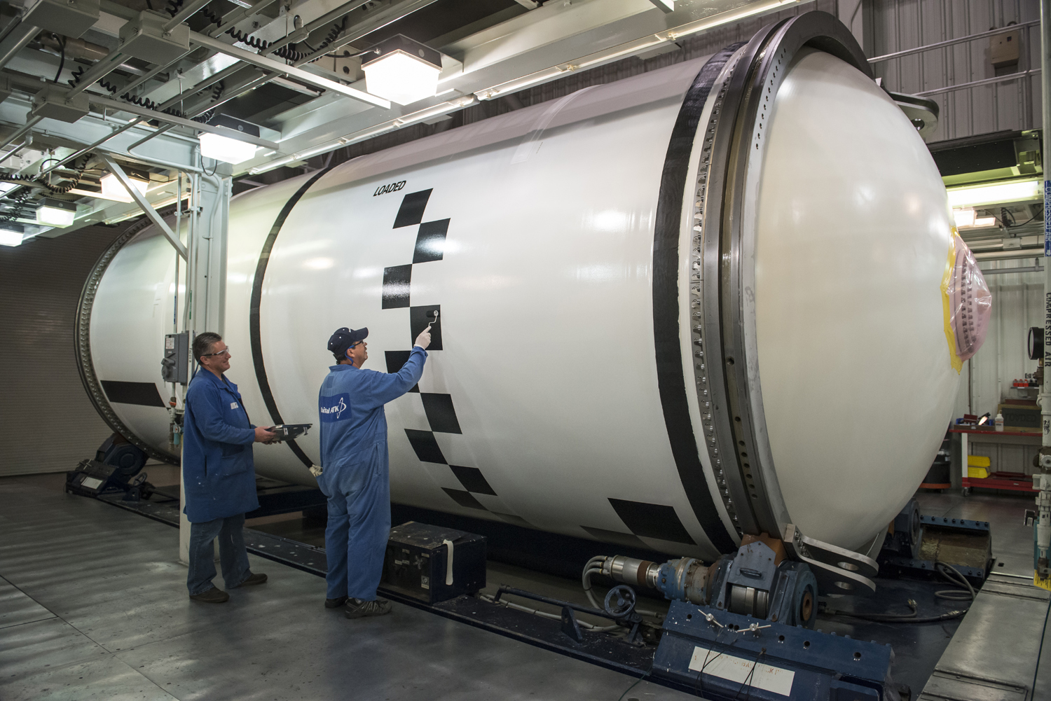 Technicians apply photogrammetric markings on completed segments for the solid rocket booster motors.