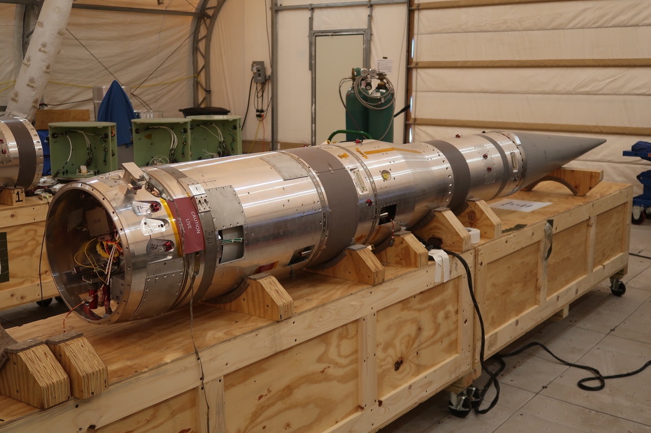 The payload section of a sounding rocket sits on a wooden box.