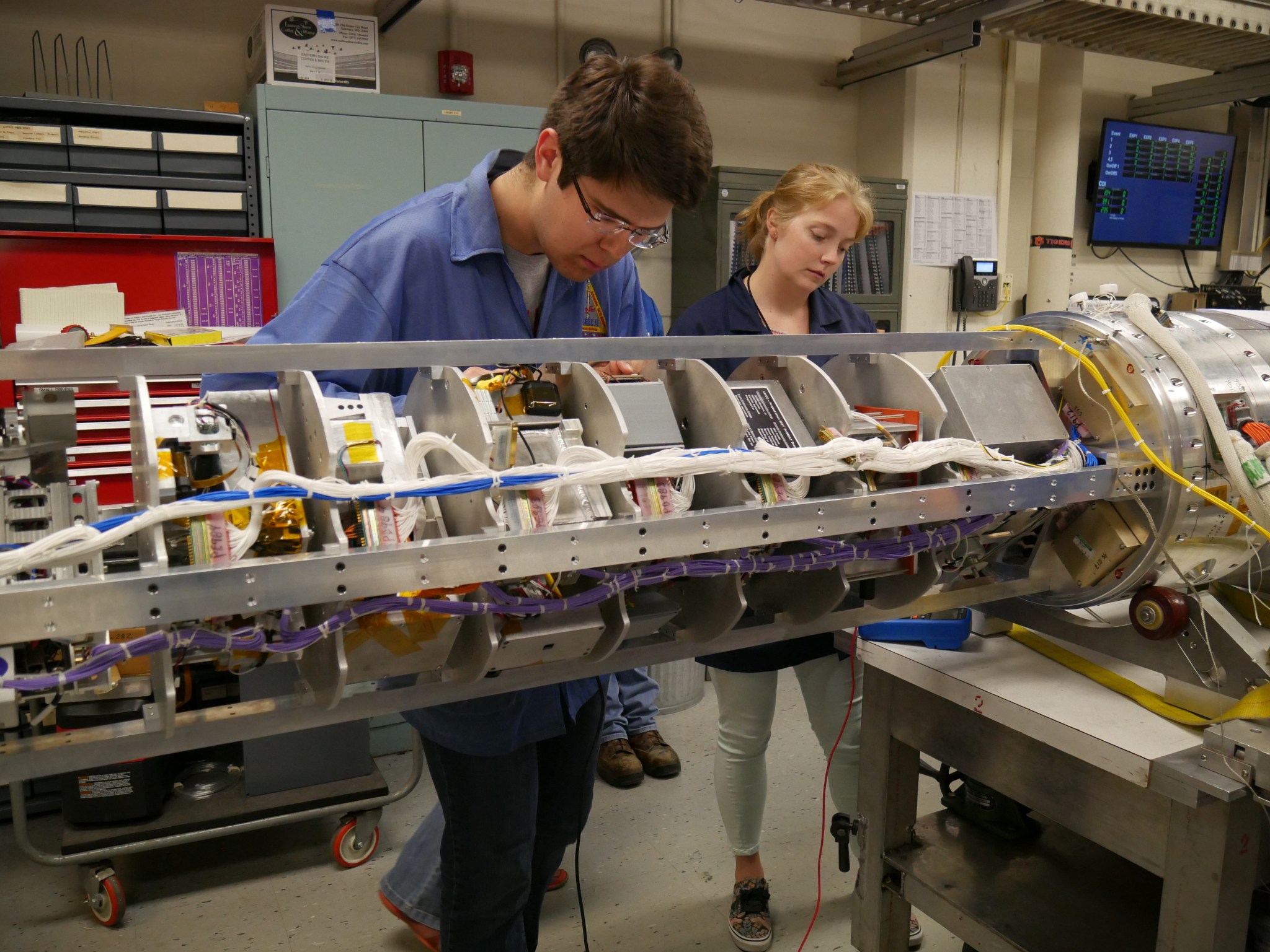 Students work on the inside of a sounding rocket payload.