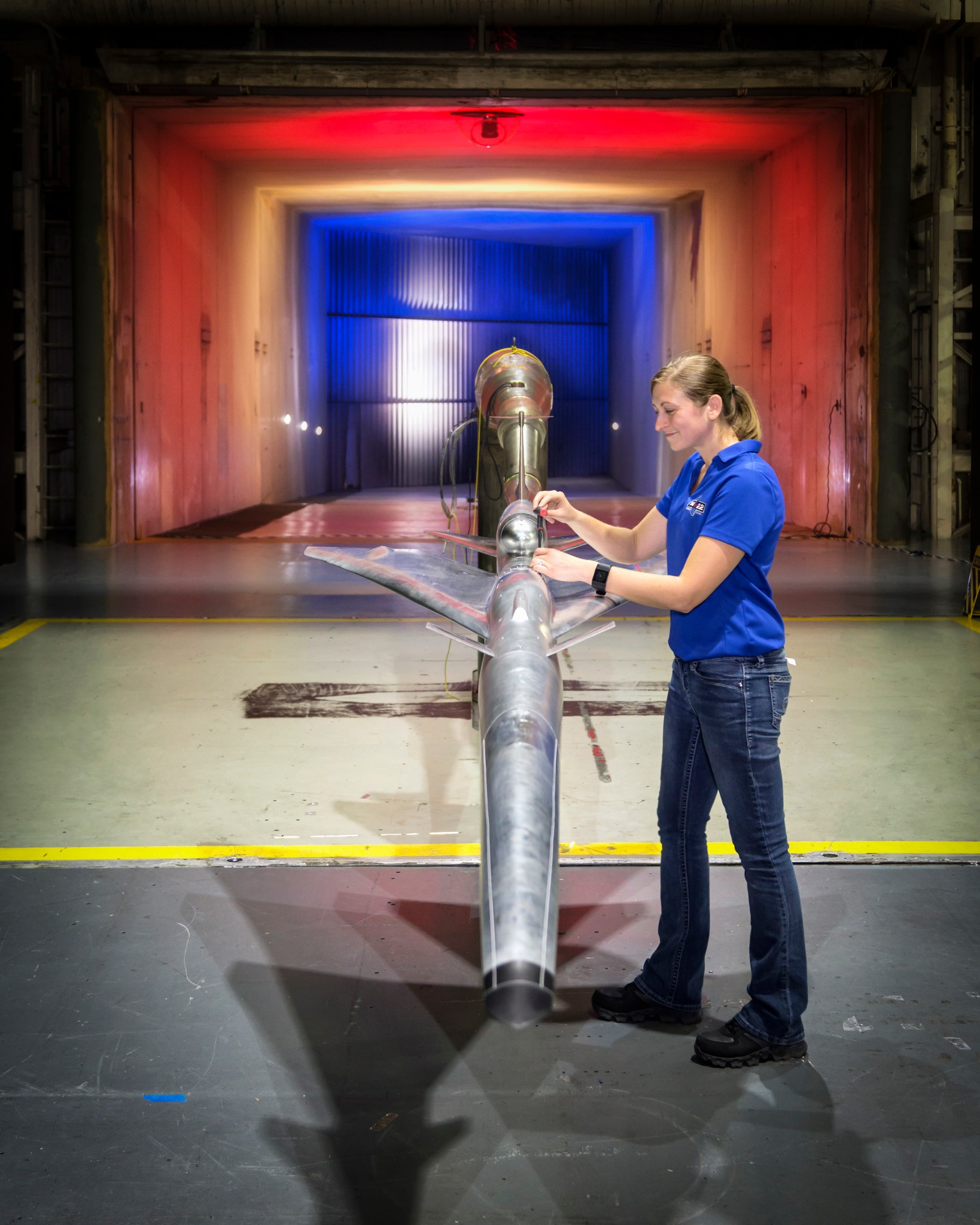 Engineer stands with X-plane design model in wind tunnel