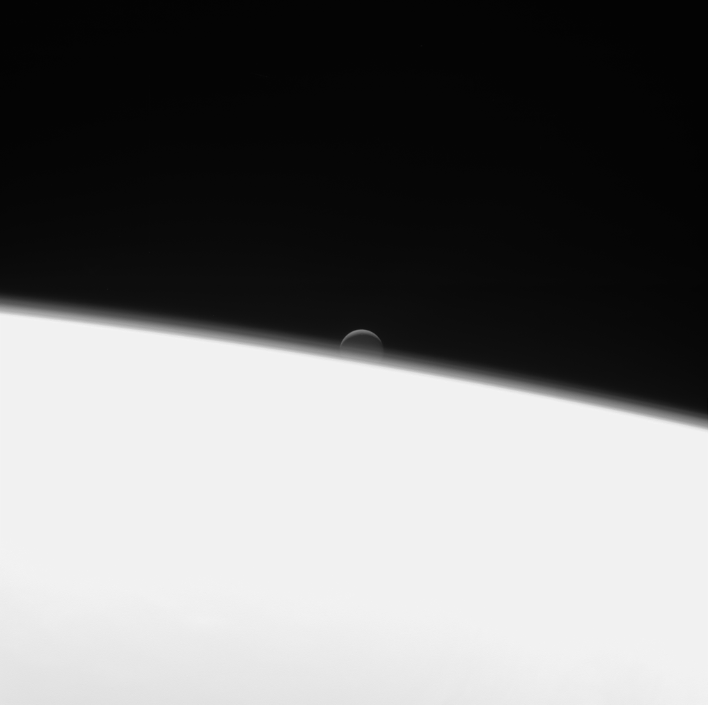 Moon Enceladus in distance behind Saturn