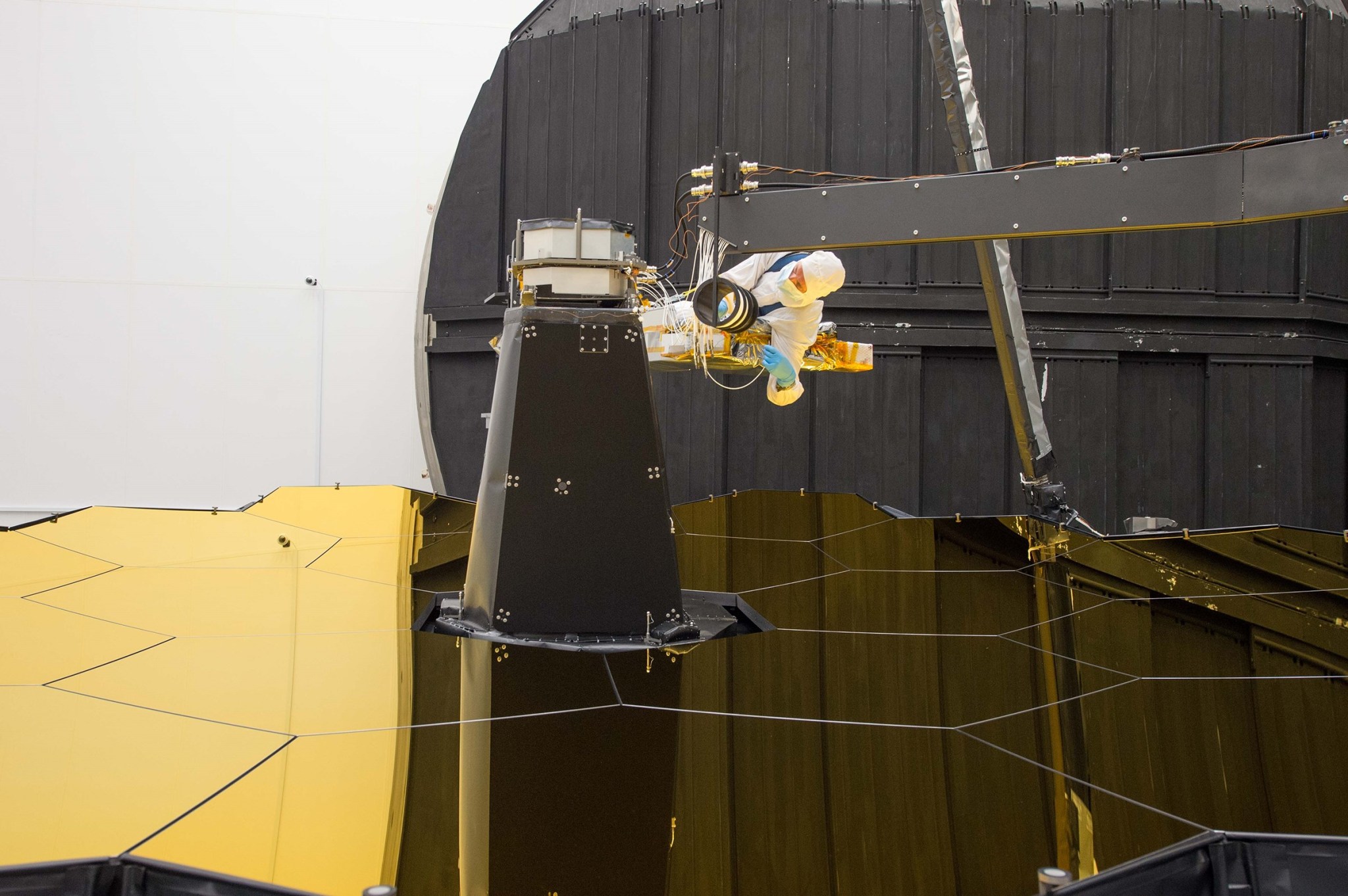 Ball Aerospace optical engineer Larkin Carey is shown connecting fiber optics to the AOS Source Plate Assembly.