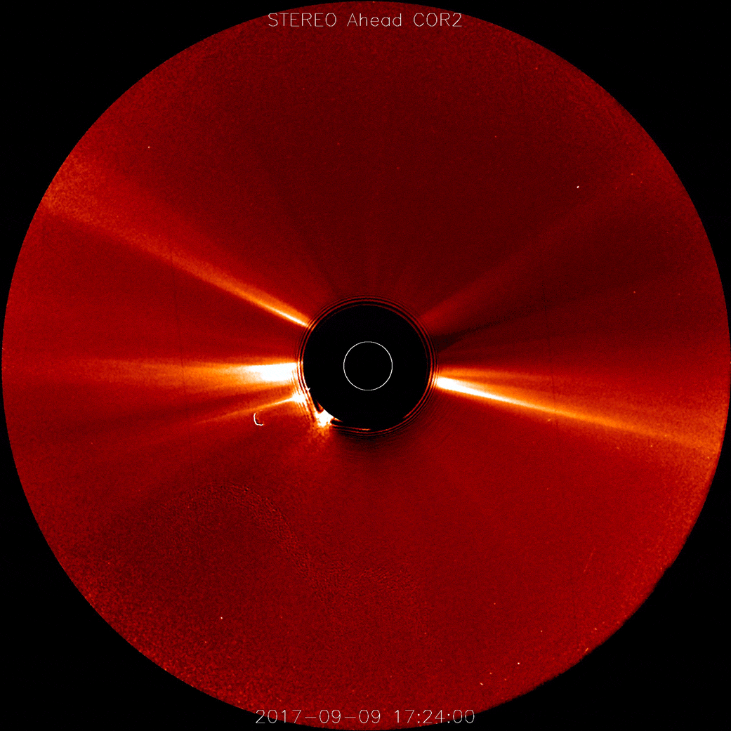 Satellite image of the Sun's corona. A black disk blocks out the Sun. A red CD-shaped image shows bright white and yellow light streaming out from one side.