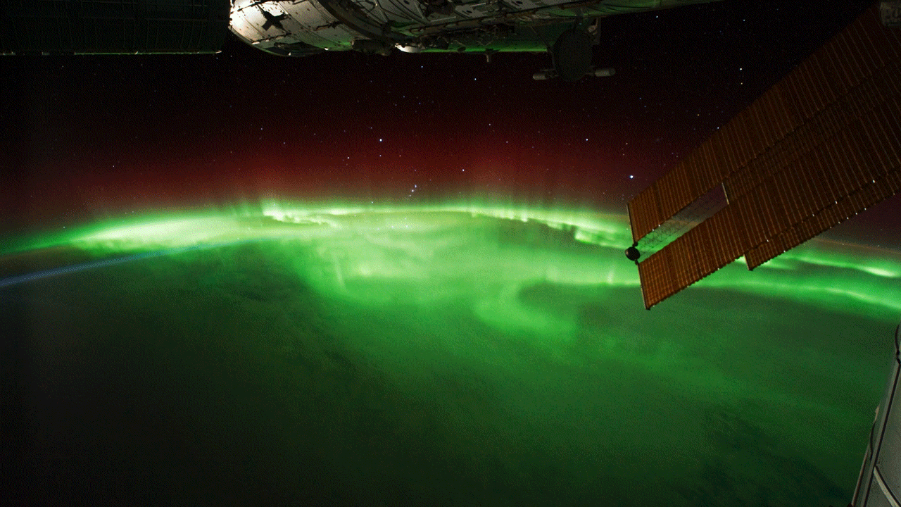 An animated move shows green aurora above Earth as observed from the International Space Station