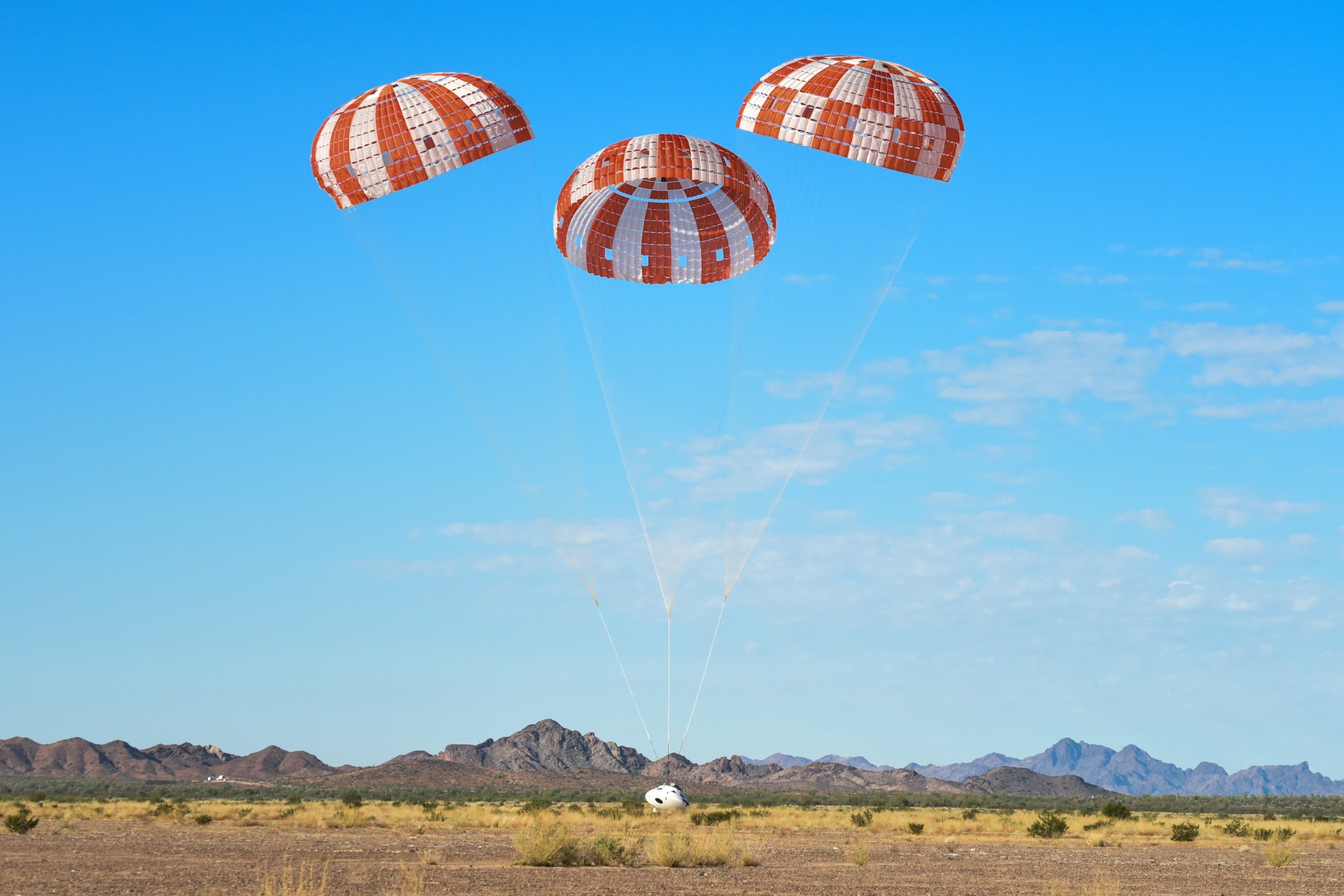Orion spacecraft with parachutes deployed descends to Earth