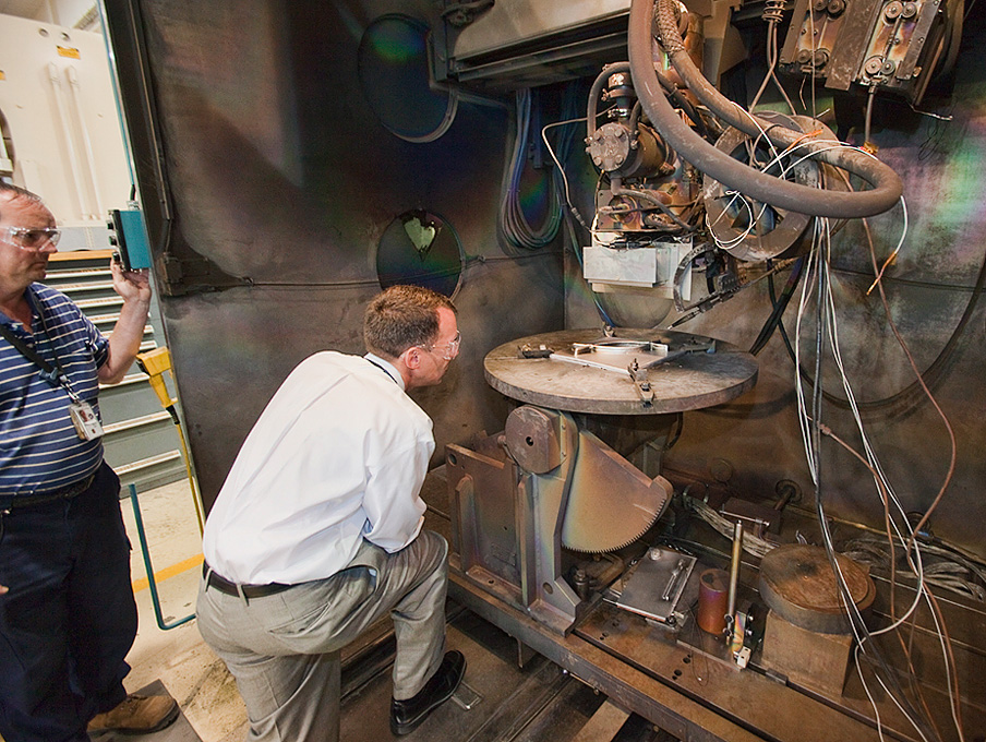 Two researchers examine the results of a 3D-printer-like machine that uses electron beams.