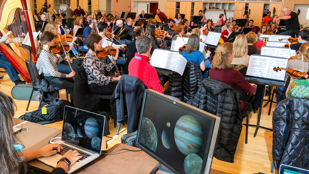 musicians perform beyond screens displaying planets
