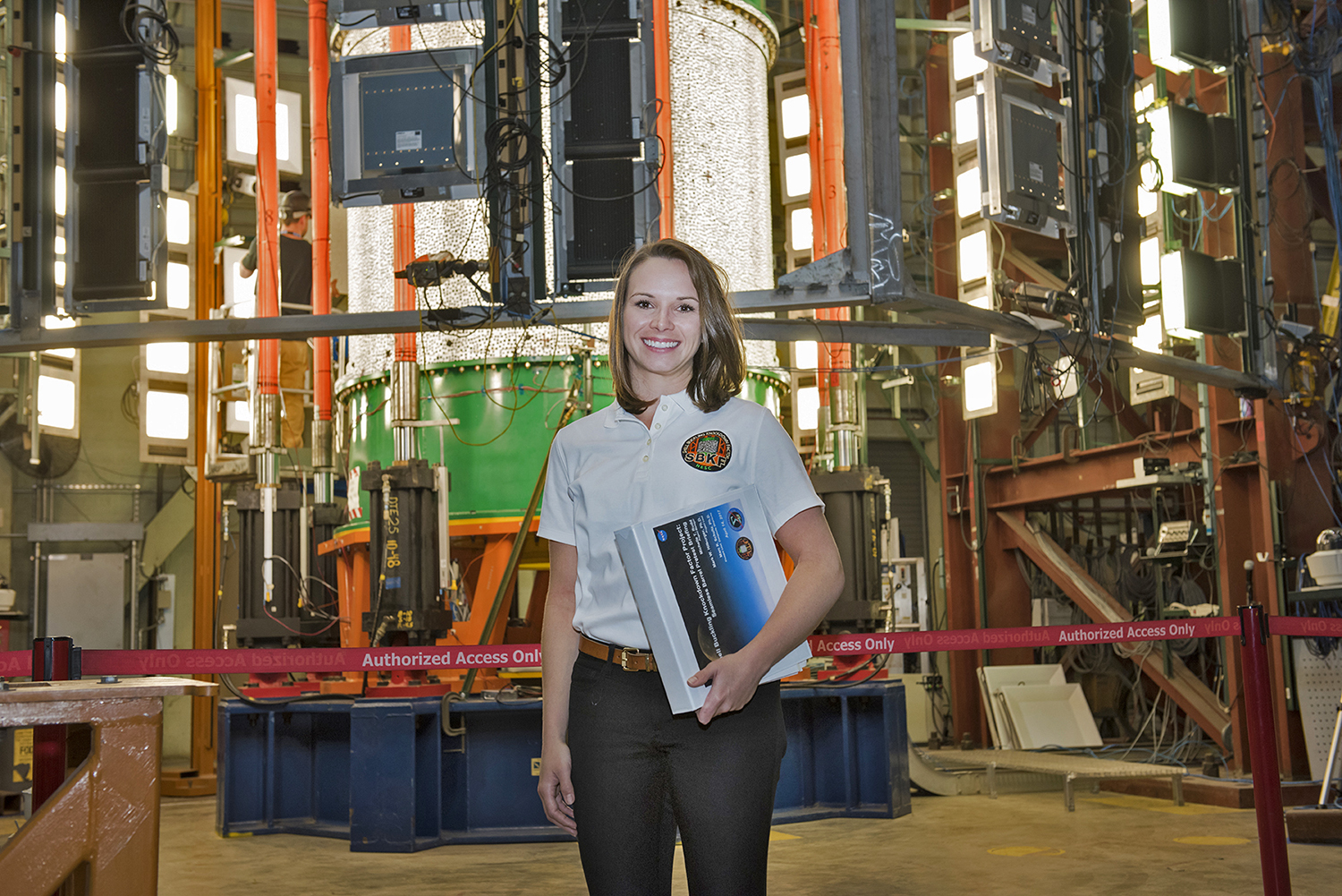 Michelle Rudd pictured with the seamless barrel test article in the test fixture at MSFC.