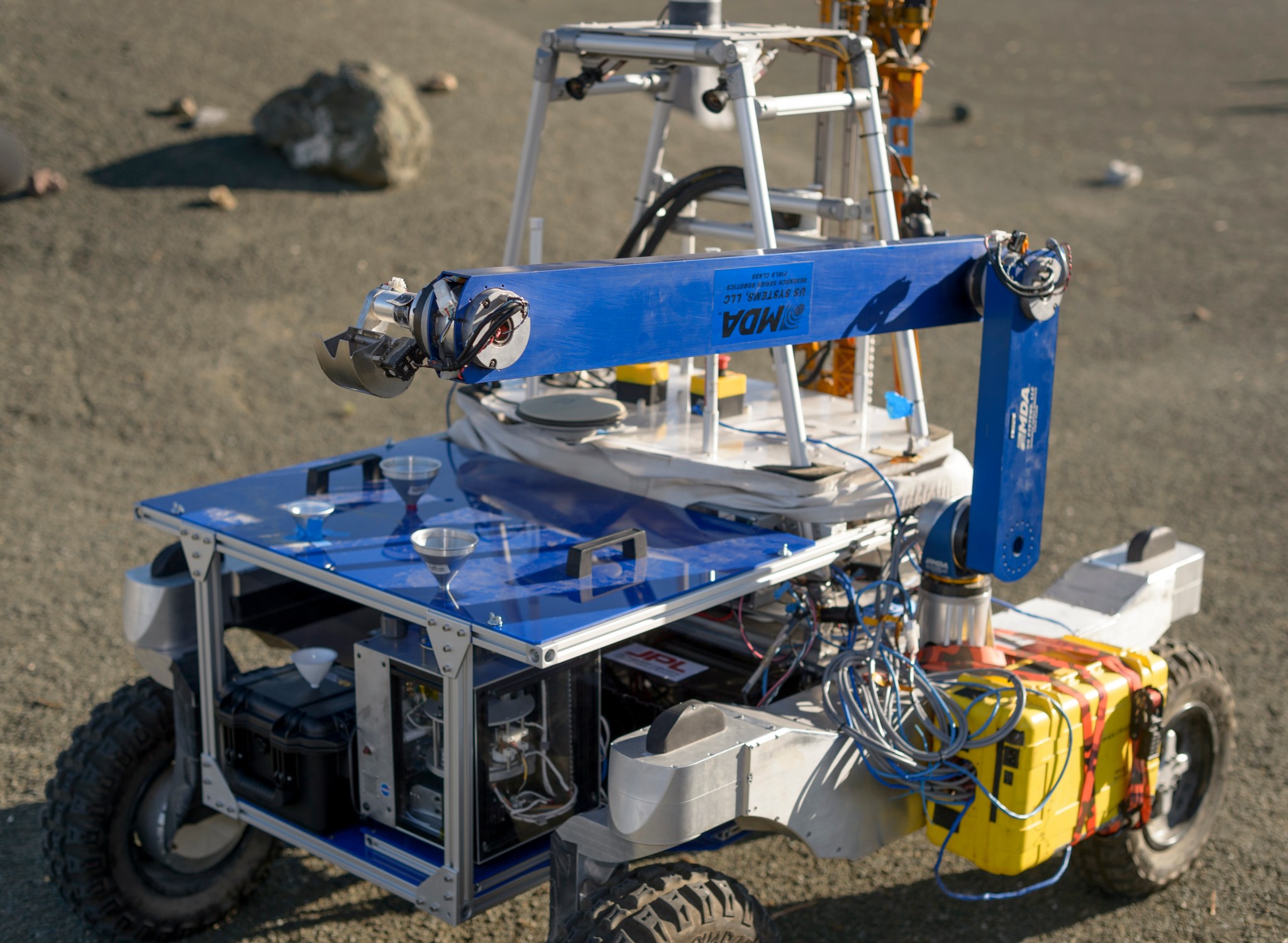 The metal scoop at the end of the robotic arm delivers soil samples through the funnels to life-detection instruments below.