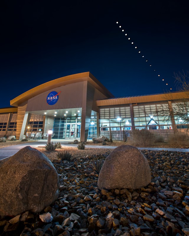 Front view of NASA Armstrong's mission support building with a composite of several images of the eclipsed moons overhead.