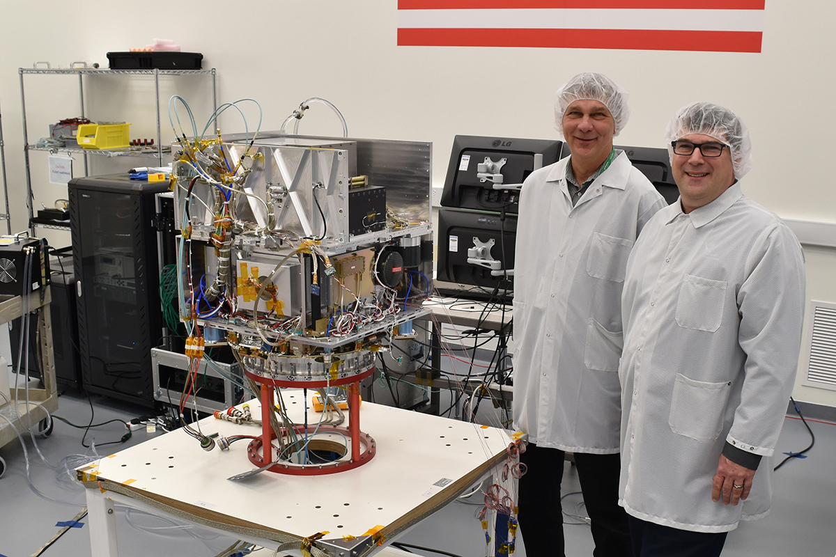 Tom Cwik, the head of JPL's Space Technology Program (left) and Allen Farrington, JPL Deep Space Atomic Clock Project Manager, view the integrated Atomic Clock Payload on General Atomics Electromagnetic Systems US's Orbital Test Bed Spacecraft.