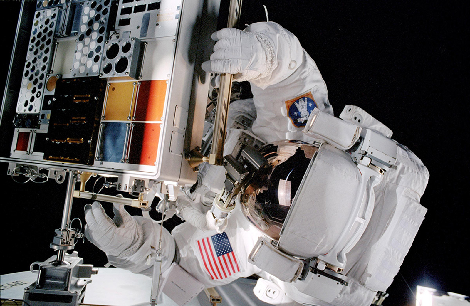 An astronaut mounts a previous version of the MISSE hardware to the International Space Station during a spacewalk.
