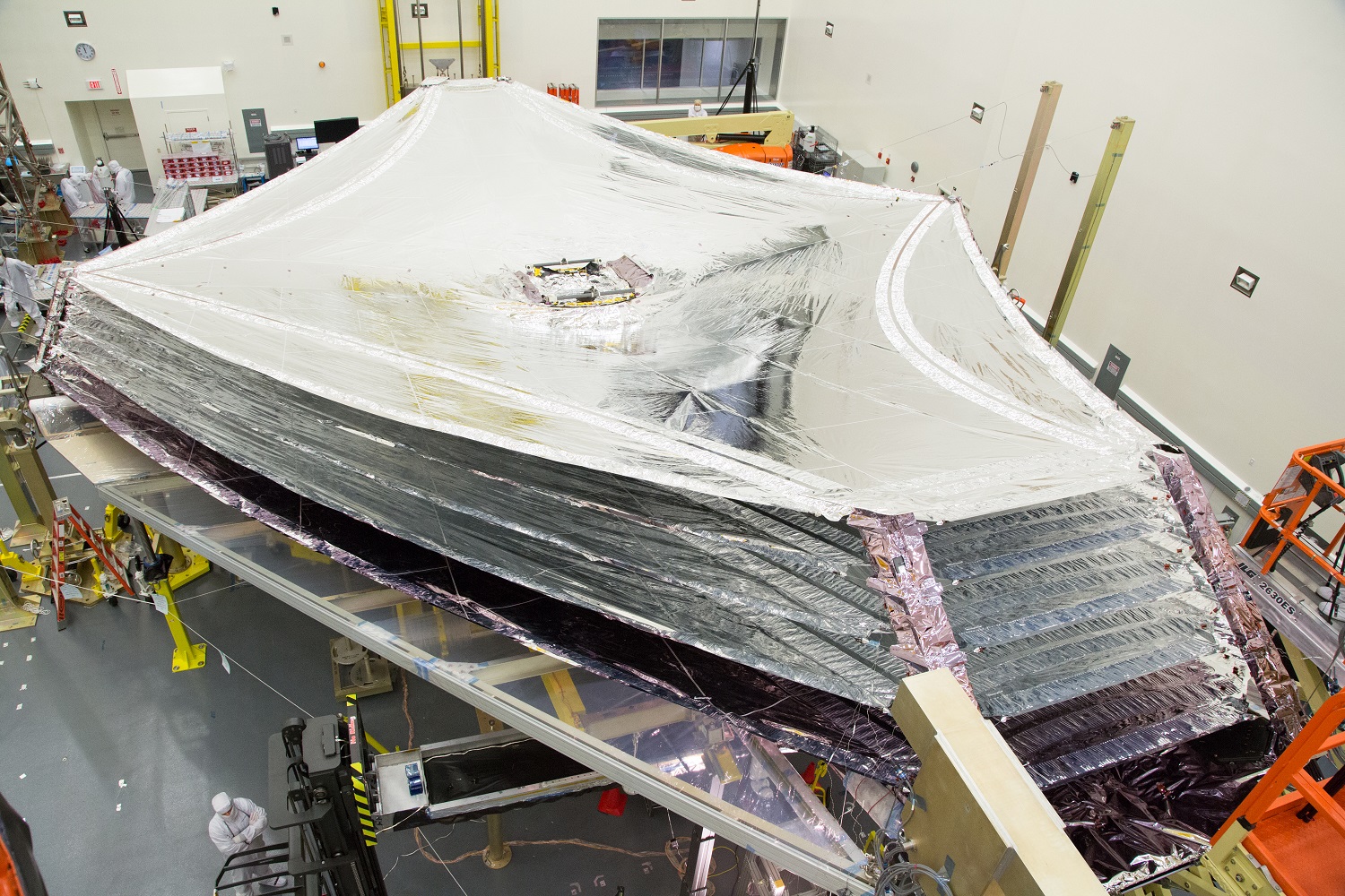 The sunshield of NASA’s James Webb Space Telescope sits deployed inside a cleanroom at Northrop Grumman.