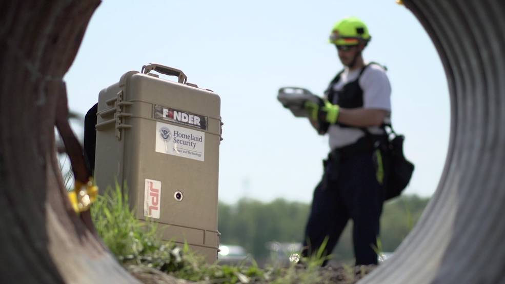 Search and rescue team member stands next to NASA FINDER tool placed on ground