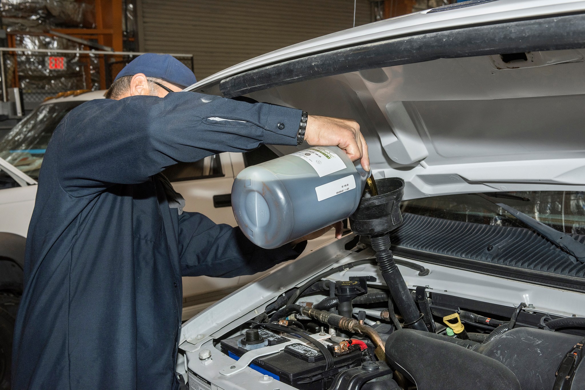 Scott Rogers pours a new bio-based synthetic engine oil into a vehicles at Armstrong.