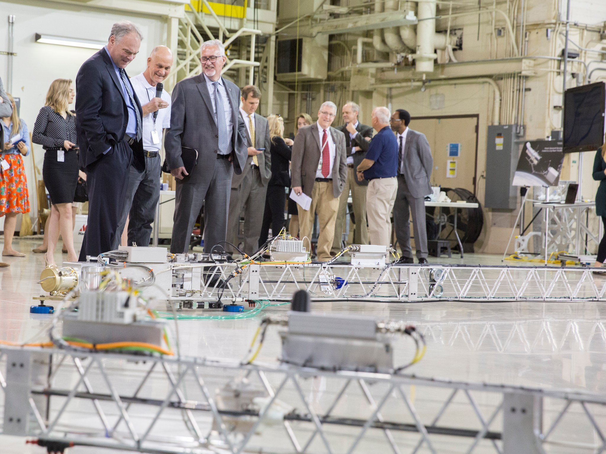 U.S. Sen. Tim Kaine, left, peers down at a test version of  Tension Actuated in Space MANipulator (TALISMAN).