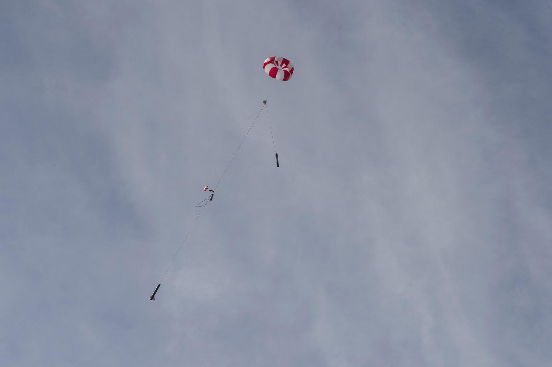 A rocket descends on its parachutes