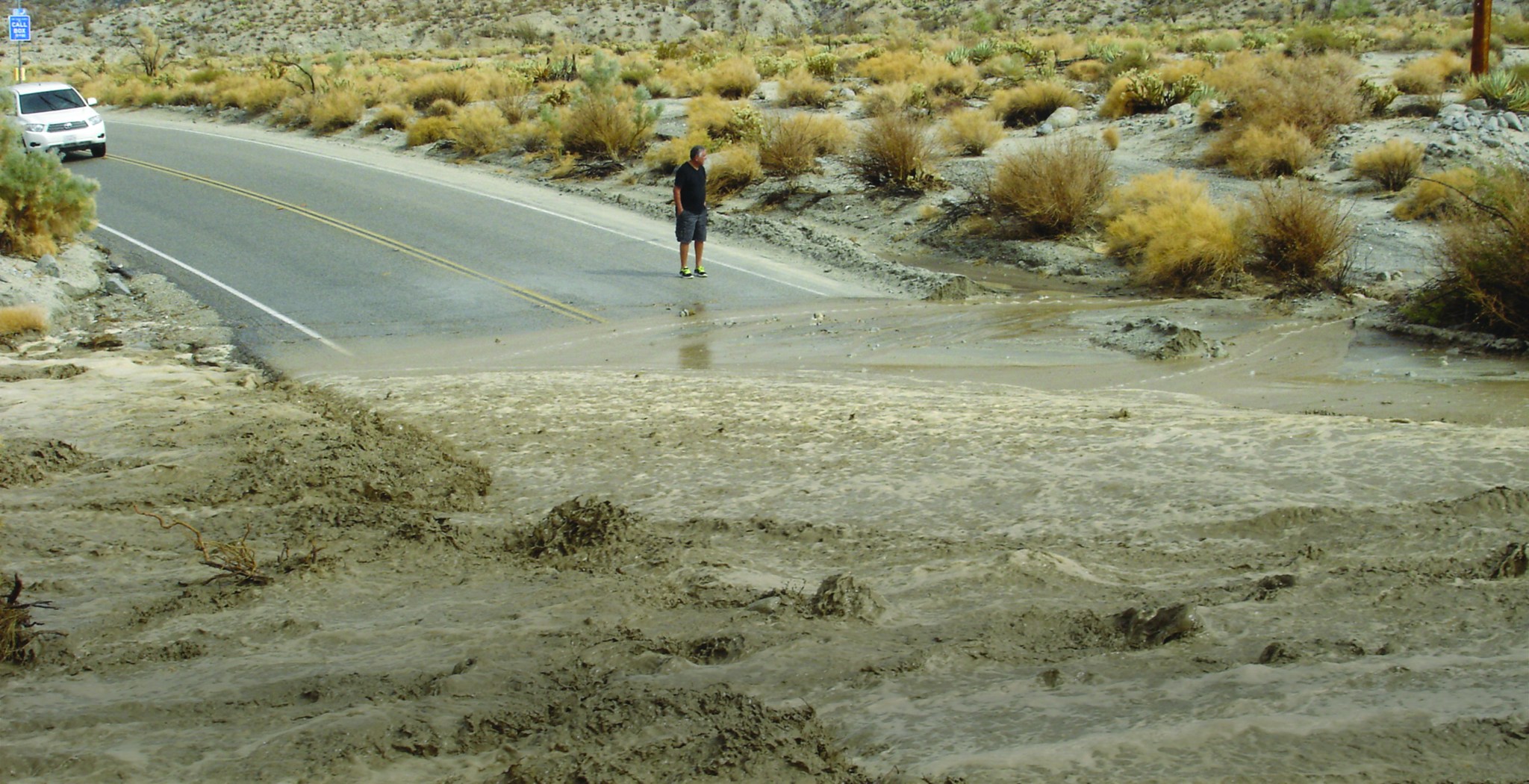 Man standing near a flooded highway.