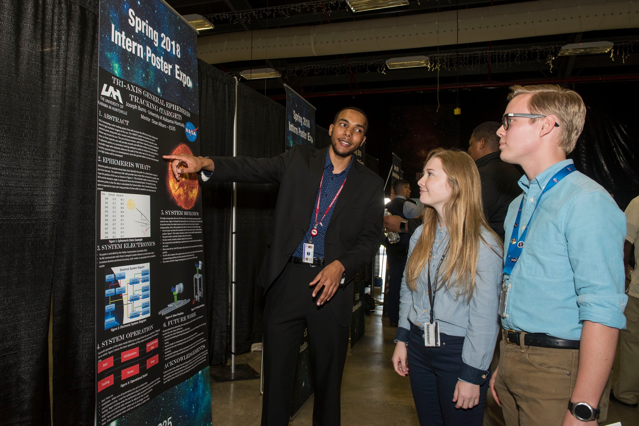 Joseph Burns, left, shares his poster highlighting the findings of his internship with Amber Rampey, center, and David Hunter.