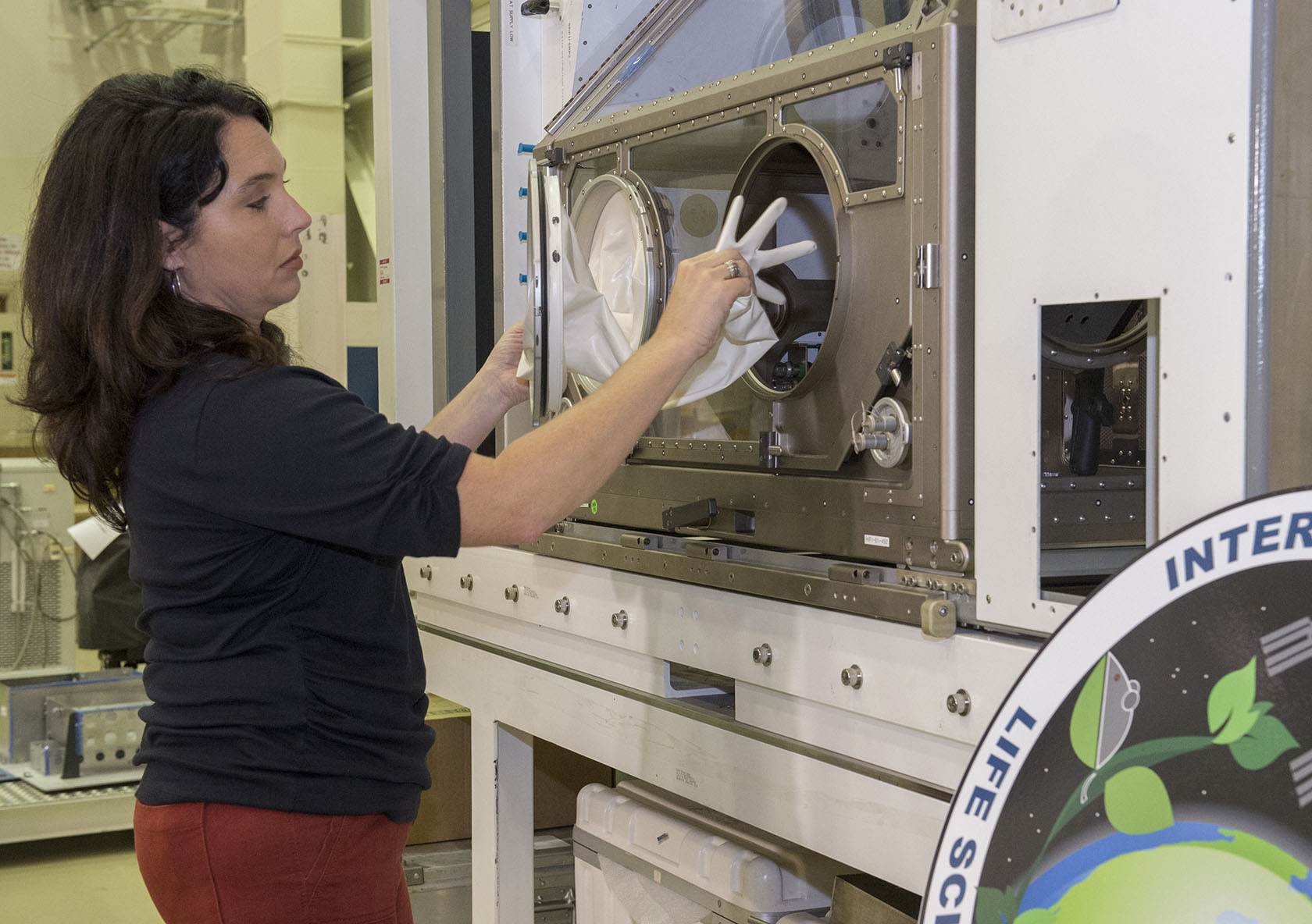 NASA Marshall Space Flight Center’s Christy Gattis demonstrates how the gloves are attached to the LSG.