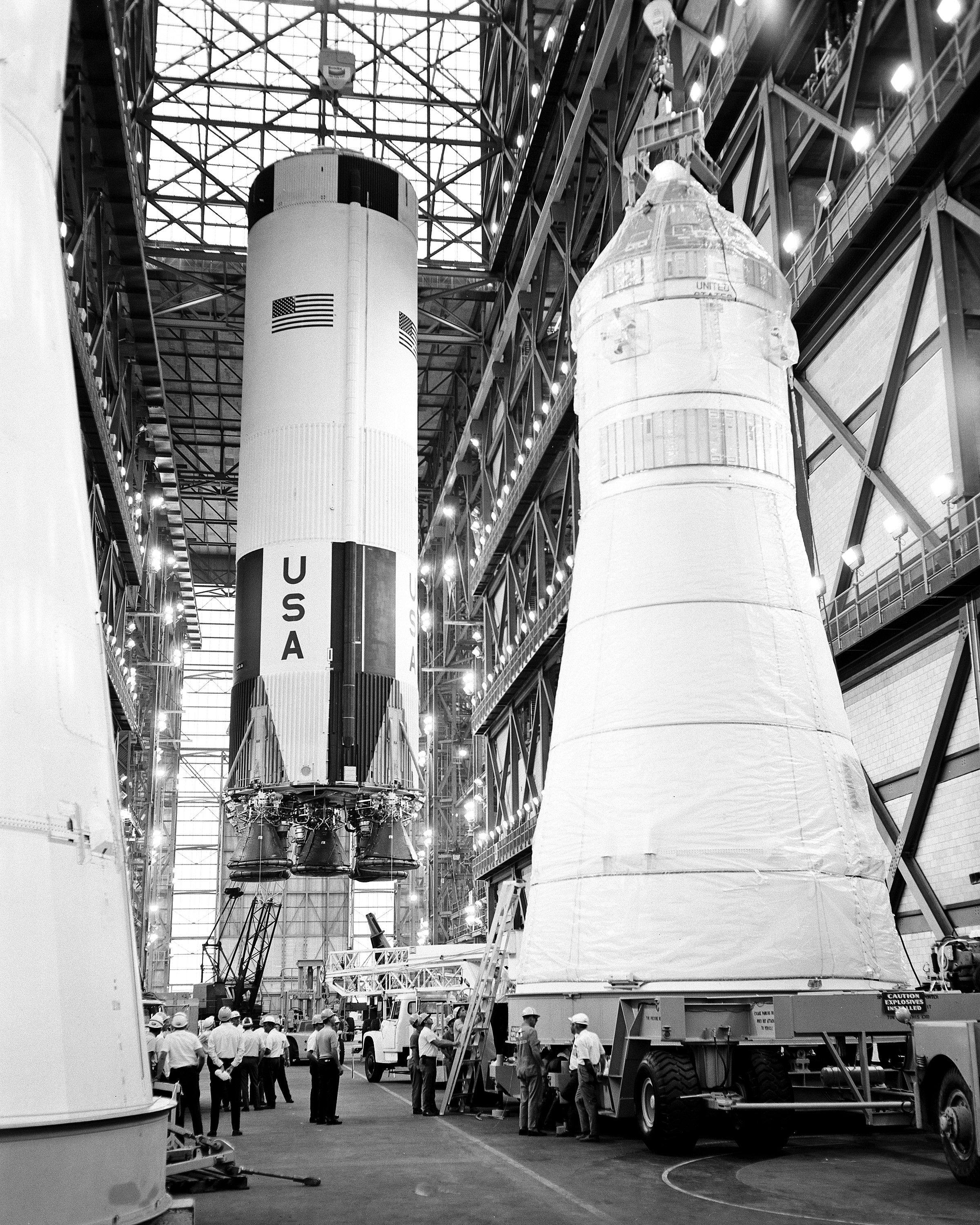 The first stage of the Apollo 10 Saturn V space vehicle is hoisted above the transfer aisle in preparation for erection on a mobile launcher within...