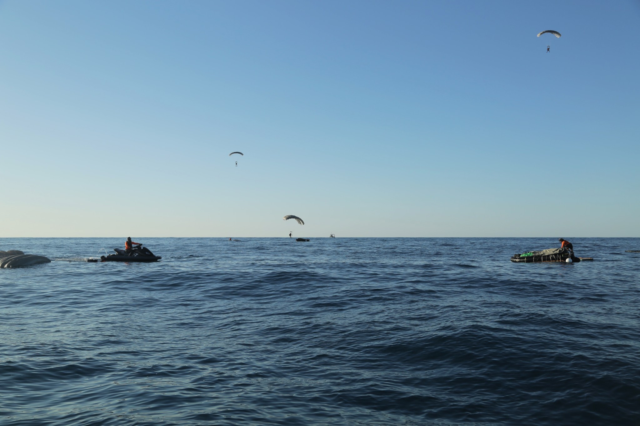 Pararescue specialists deploy their parachutes and prepare to touch down on the Atlantic Ocean surface during an astronaut rescue training exercise in April.