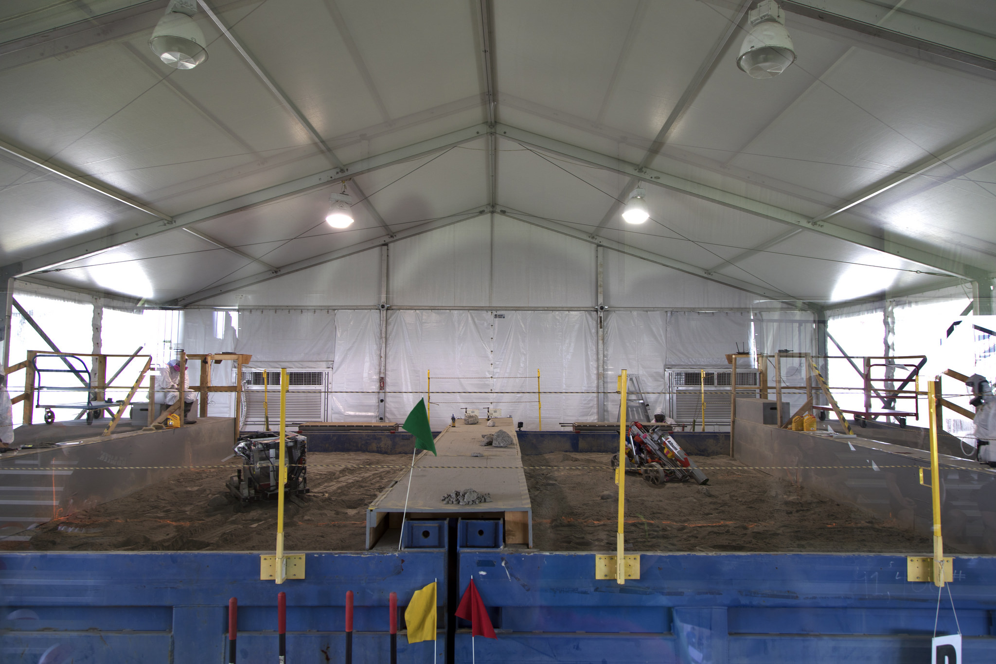 Two robot miners dig in the dirt in the mining arena during NASA's 9th Annual Robotic Mining Competition at Kennedy Space Center