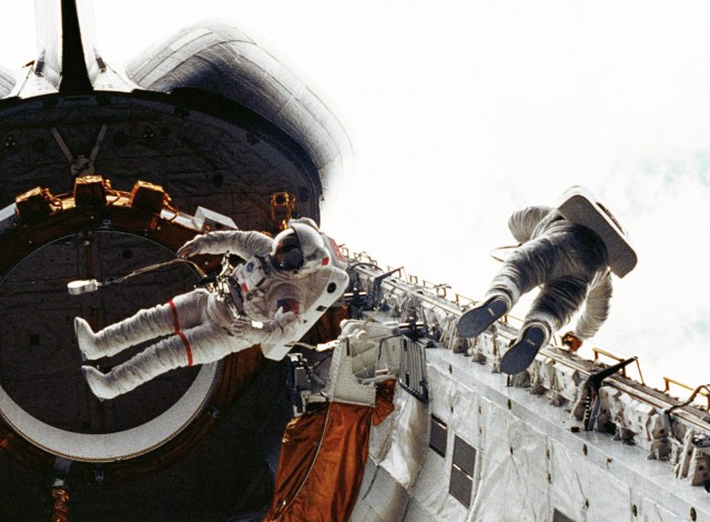 First Space Shuttle Spacewalk shows two astronauts in white space suits 'floating' in the cargo bay