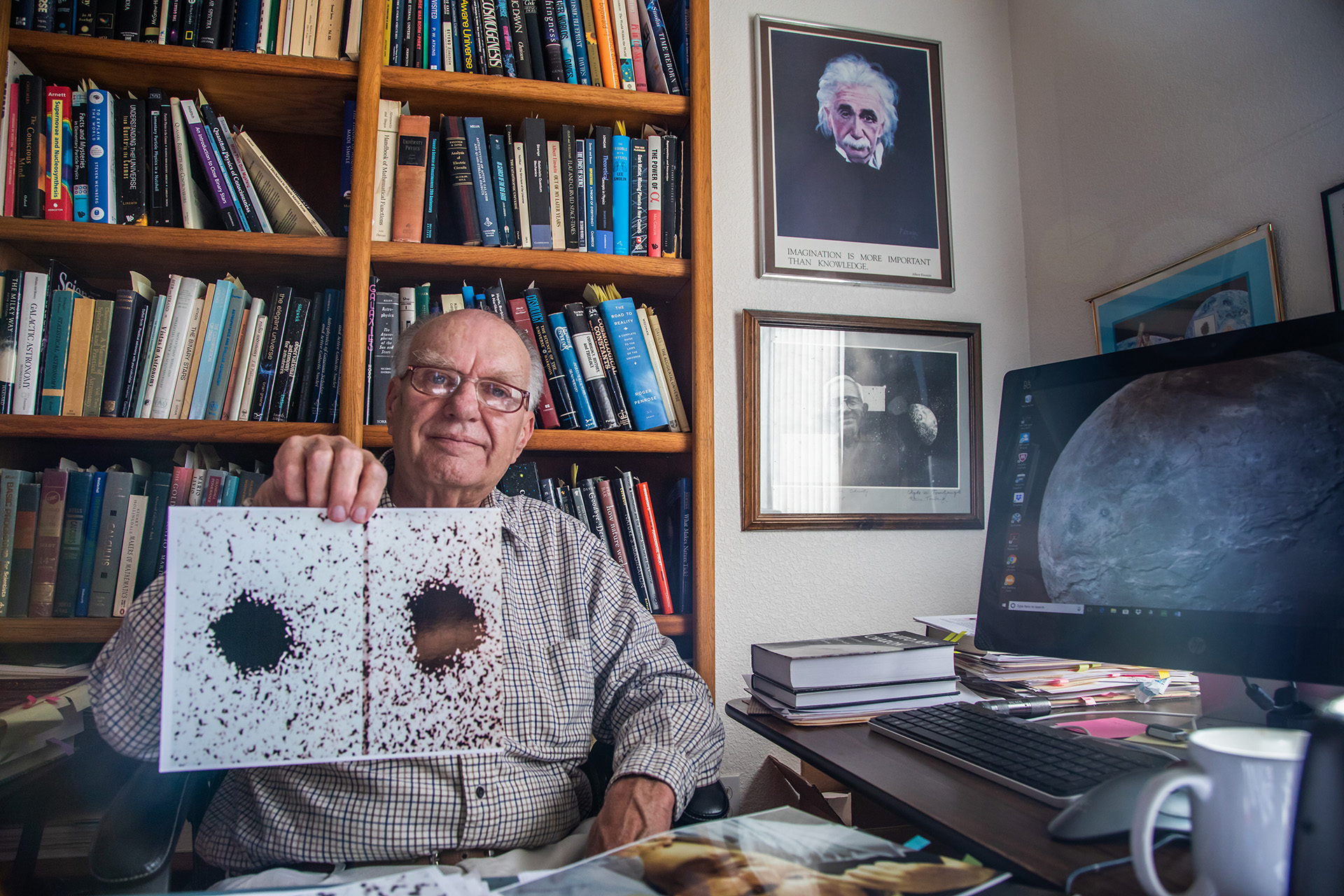 40 years after his important discovery, Jim Christy holds two of the telescope images he used to spot Pluto’s large moon Charon