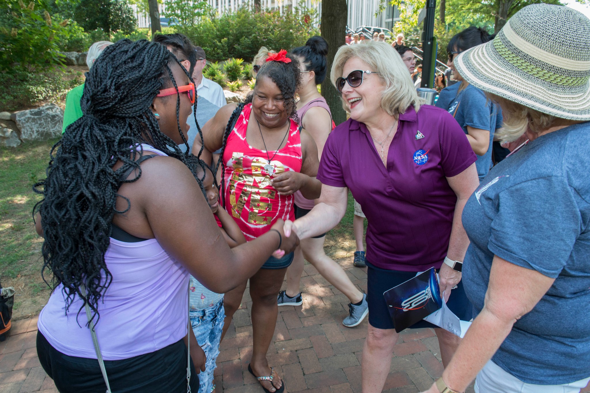 Jody Singer, second from right, greets Alyssa Slocum, left, who sang the national anthem at NASA in the Park on June 16.