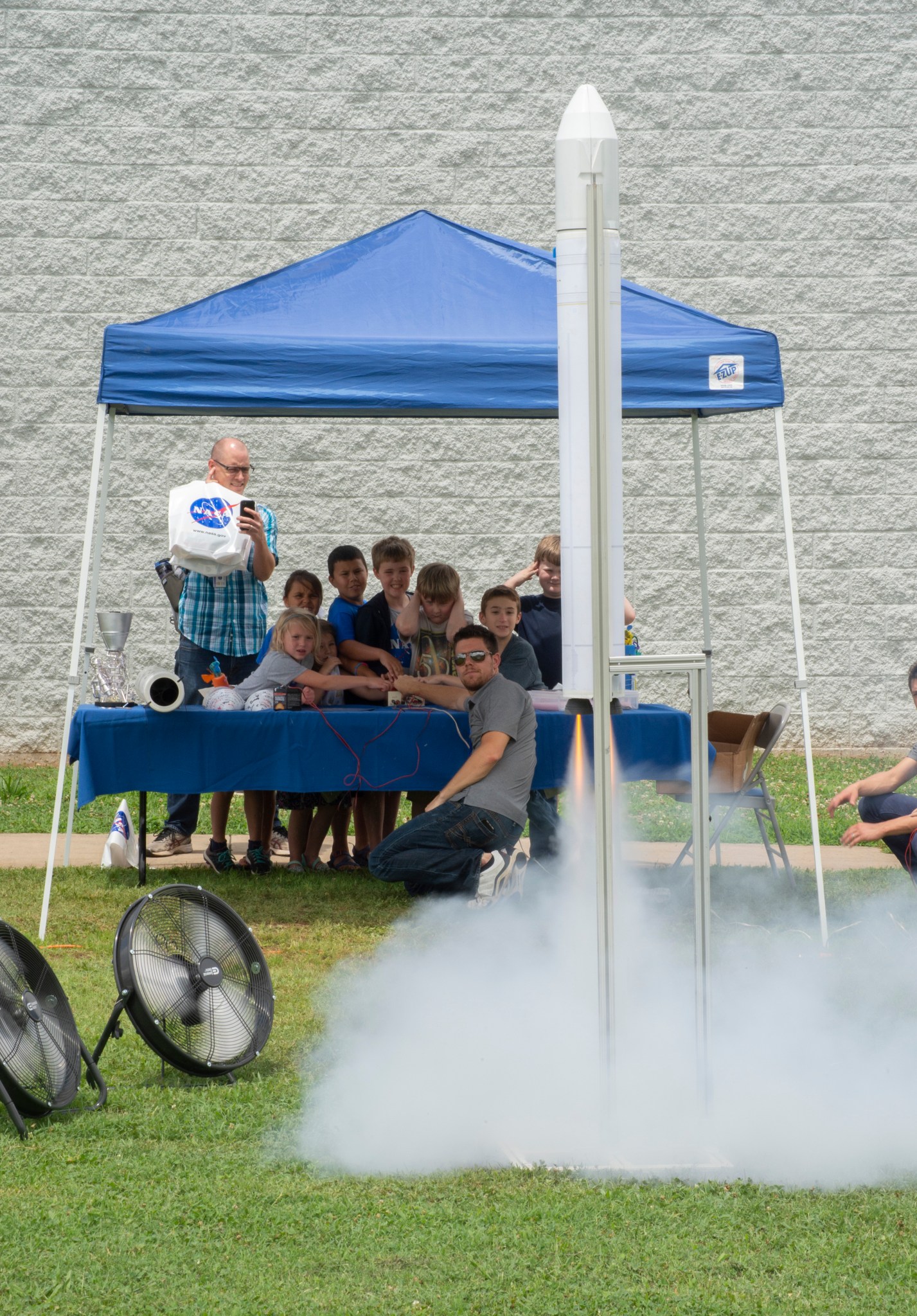 A group of excited kids press the ignition button and watch as a small rocket is test fired outside Building 4316. 