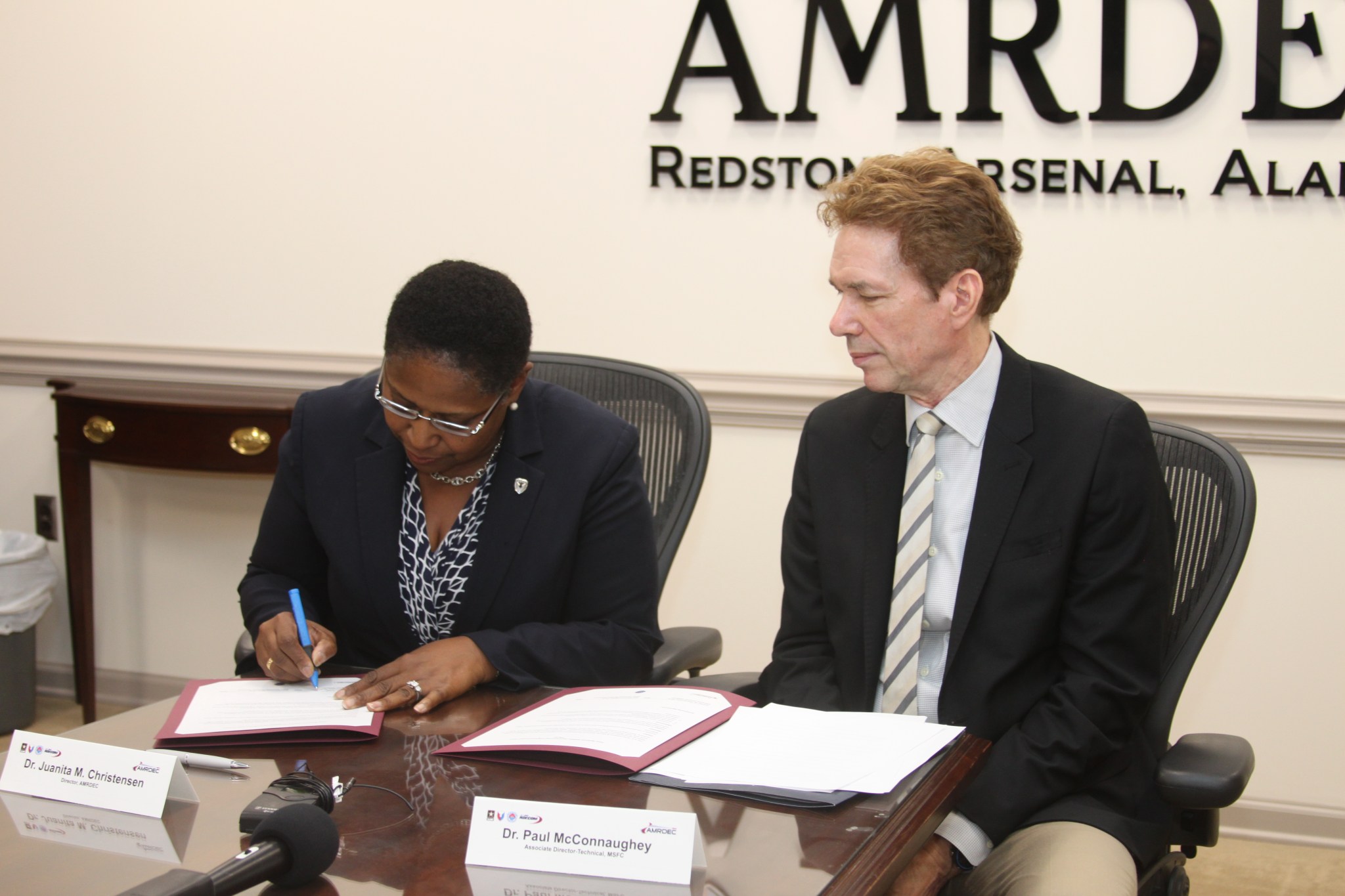 Paul McConnaughey, right, looks on as Juanita Christensen signs a renewed partner agreement Aug. 20.