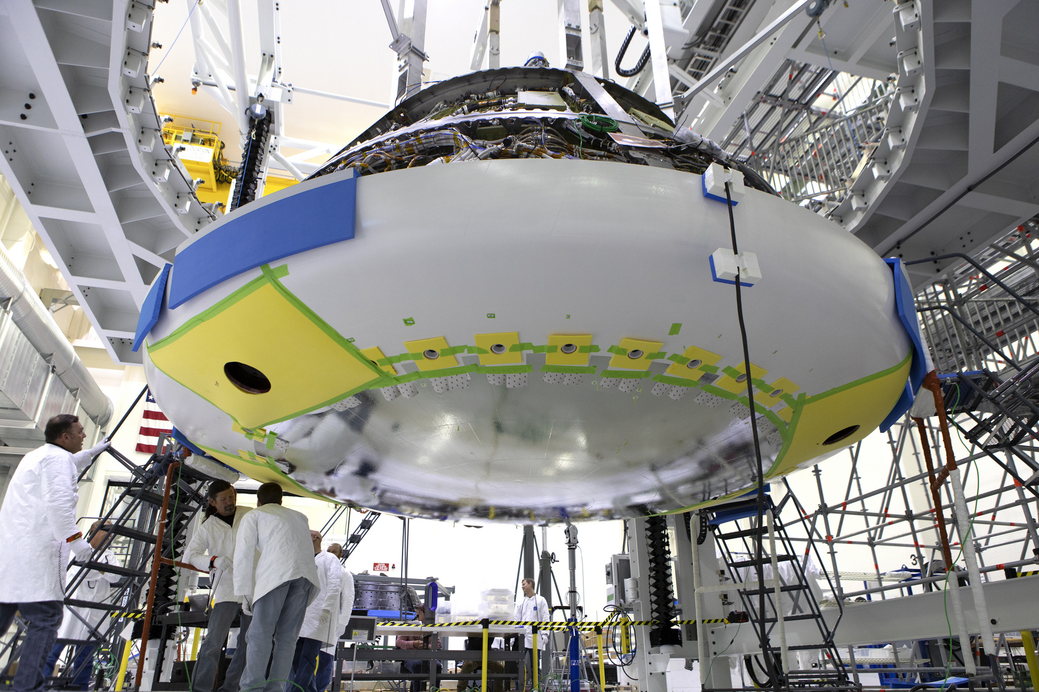 Technicians install the heat shield to the Orion crew module July 25, inside the O&C Building at Kennedy Space Center.