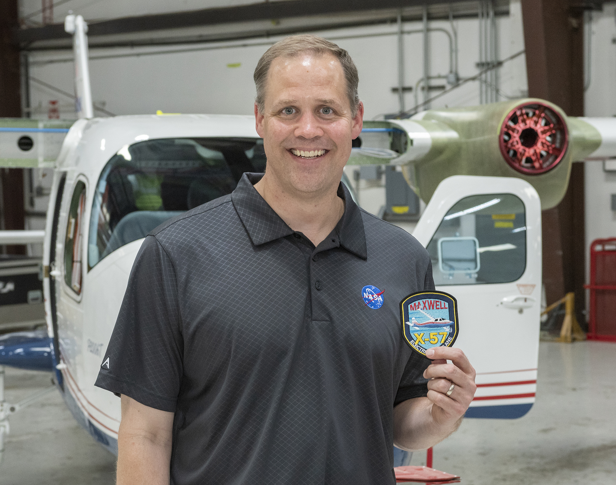 Administrator Bridenstine receives X-57 program patch standing in front of the X-57.