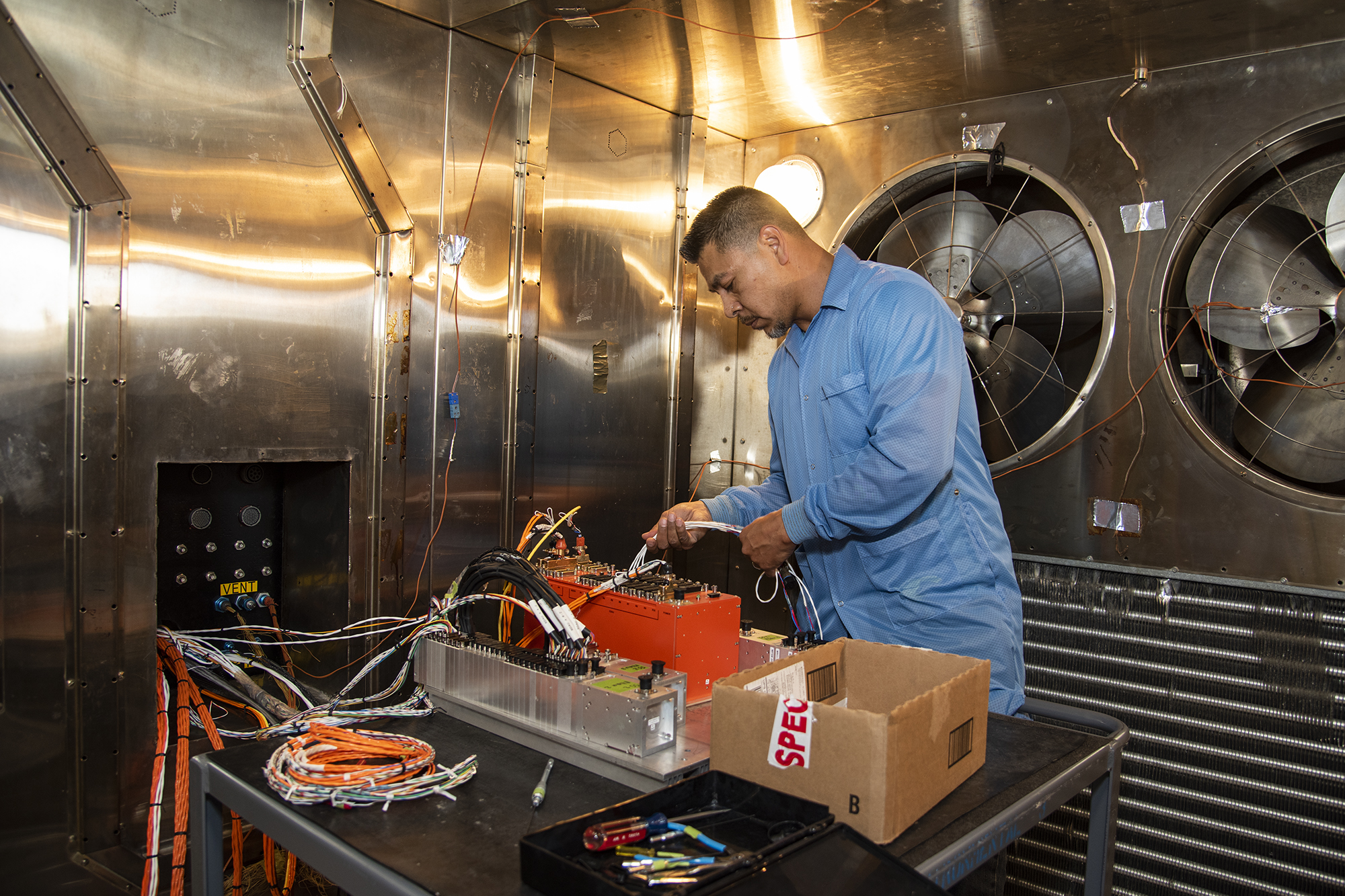 Angelo De La Rosa works inside the Environmental Laboratory’s thermal chamber to attach test articles.