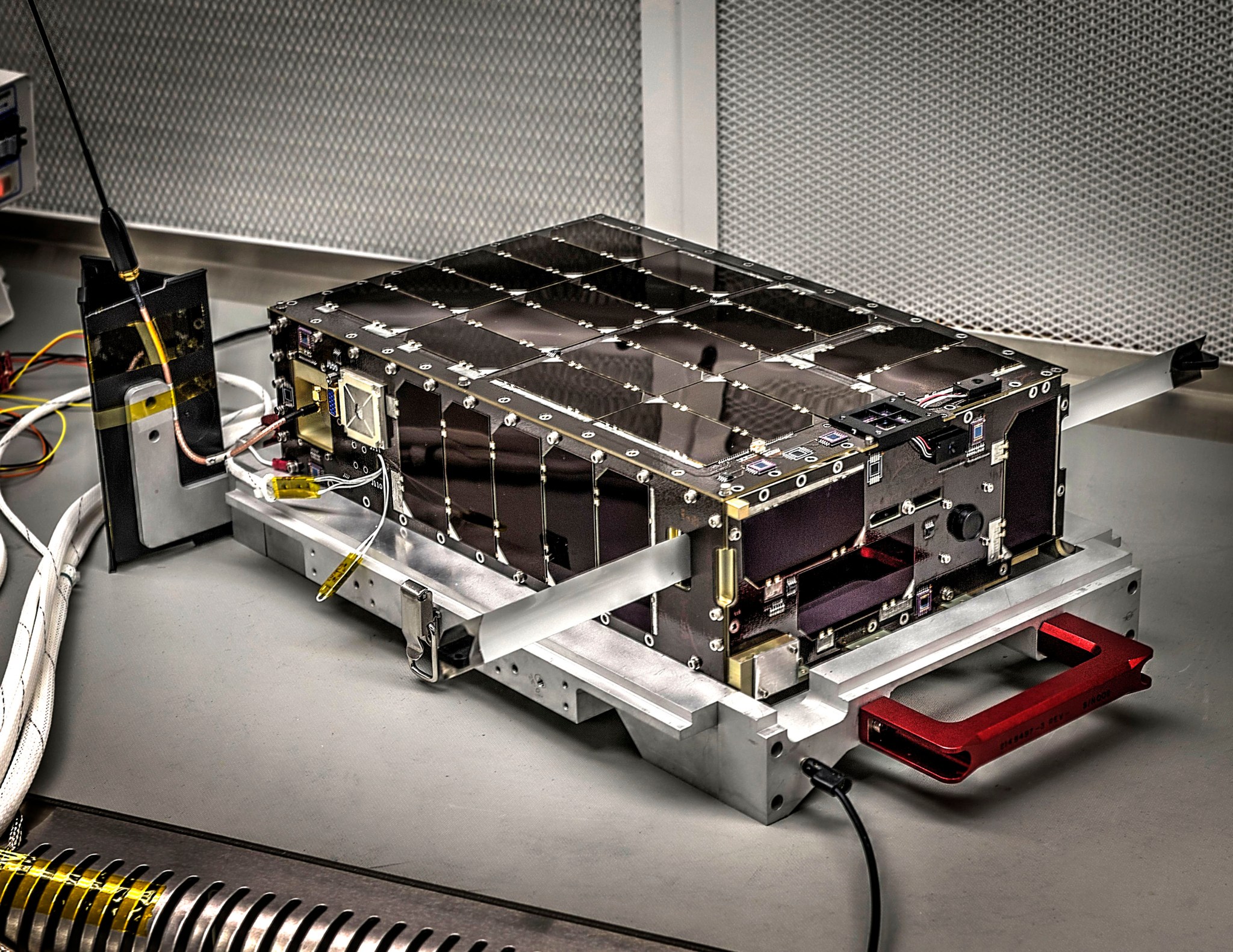 Prelaunch photo of Dellingr, a flat rectangular instrument with silver metal around its bottom. The top and sides are covered in small dark solar panels.