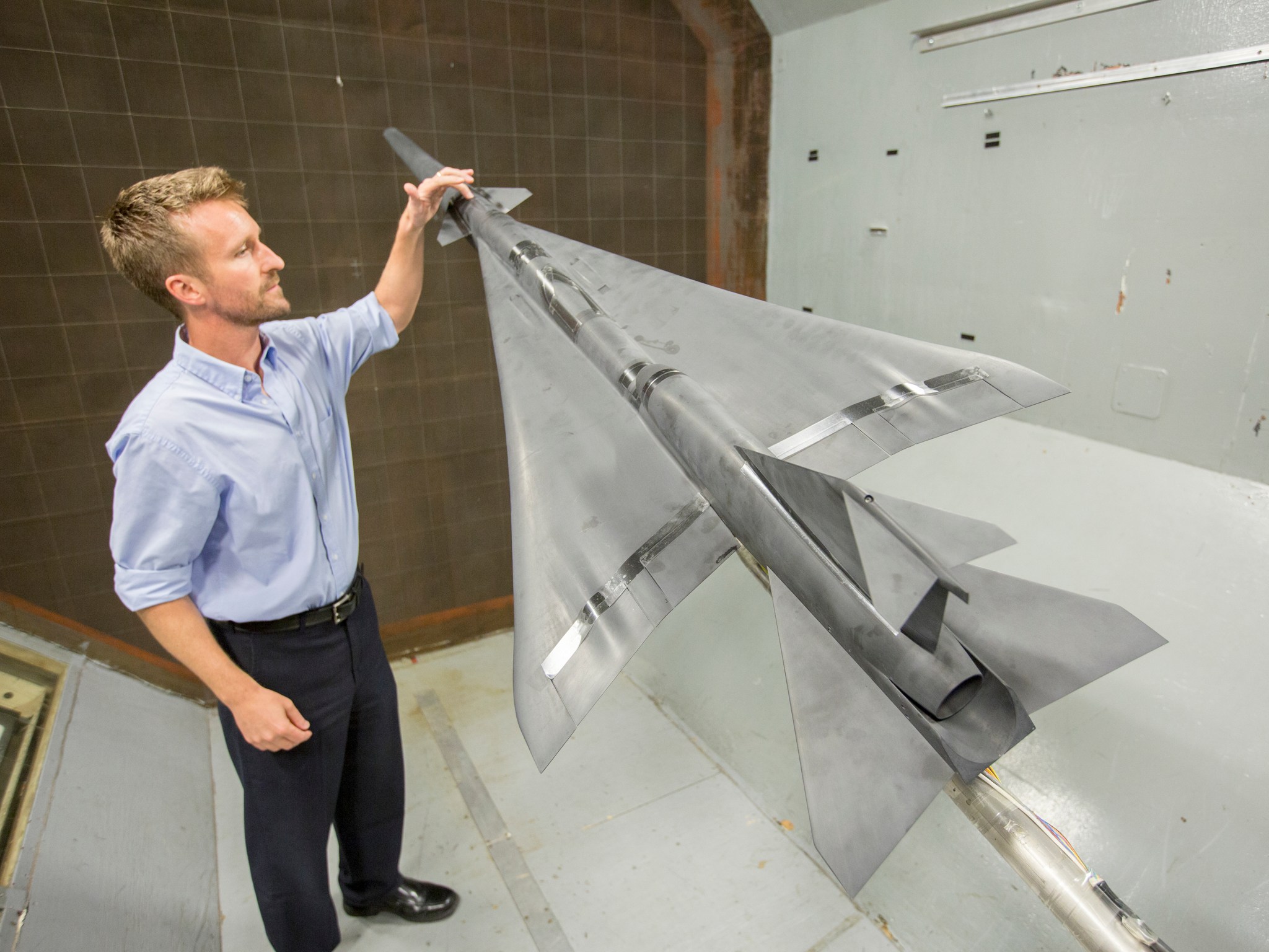 Researcher Corey Diebler inspects an eight percent scale model of the X-59 in NASA Langley's 12-Foot Low Speed Tunnel