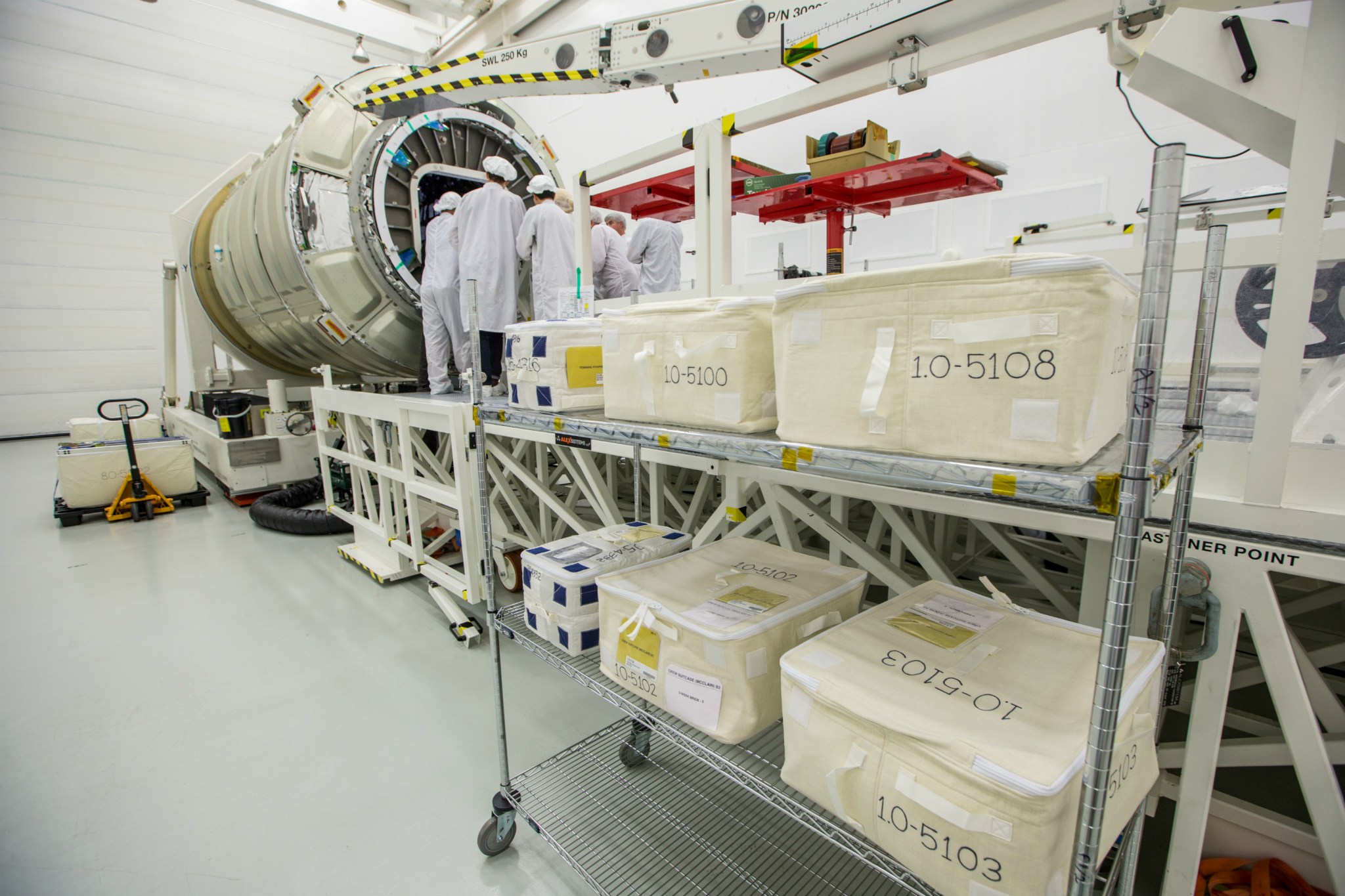 Northrop Grumman personnel load supplies and experiments into the Cygnus cargo spacecraft in the payload processing facility