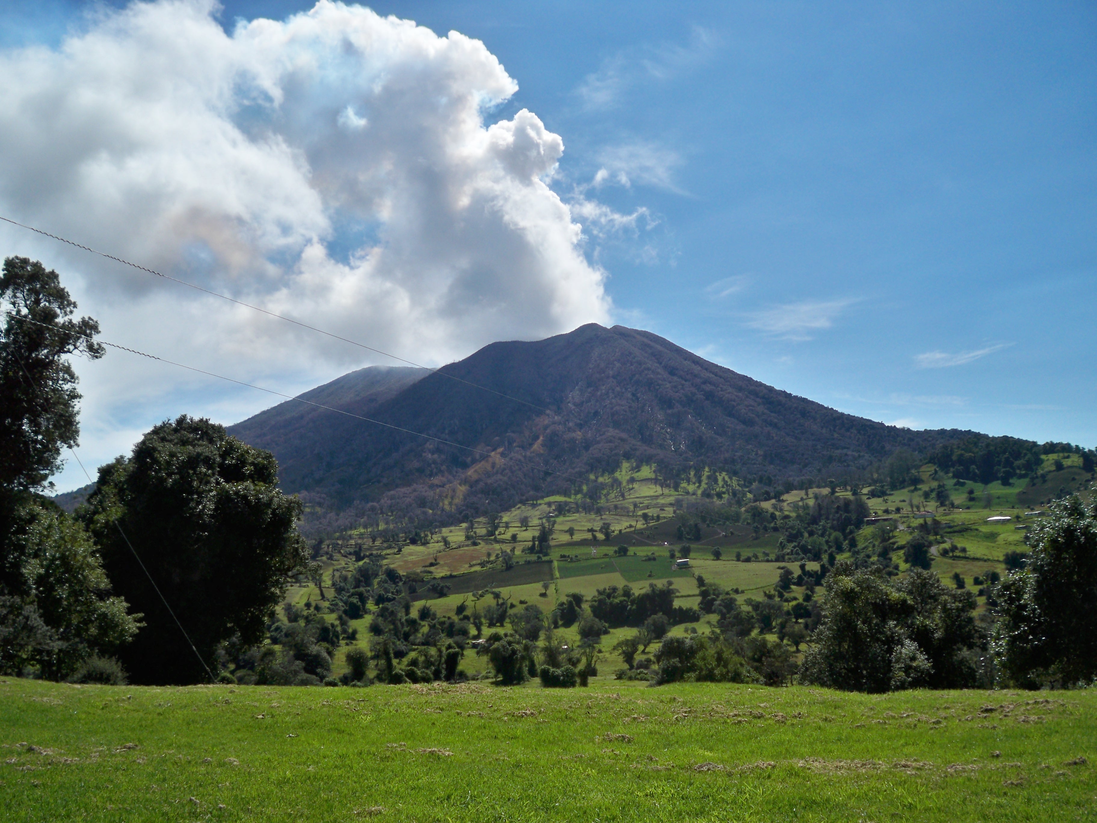 The active volcano, Turrialba, the volcano looks like a large mountain and the landscape is very green with trees. 