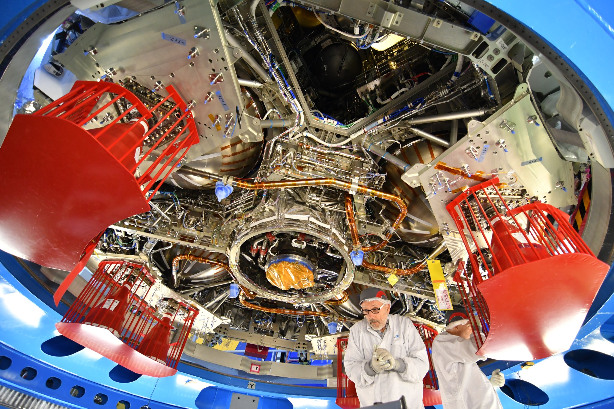 Technicians work underneath the European Service Module for NASA’s Orion spacecraft to complete final preparations