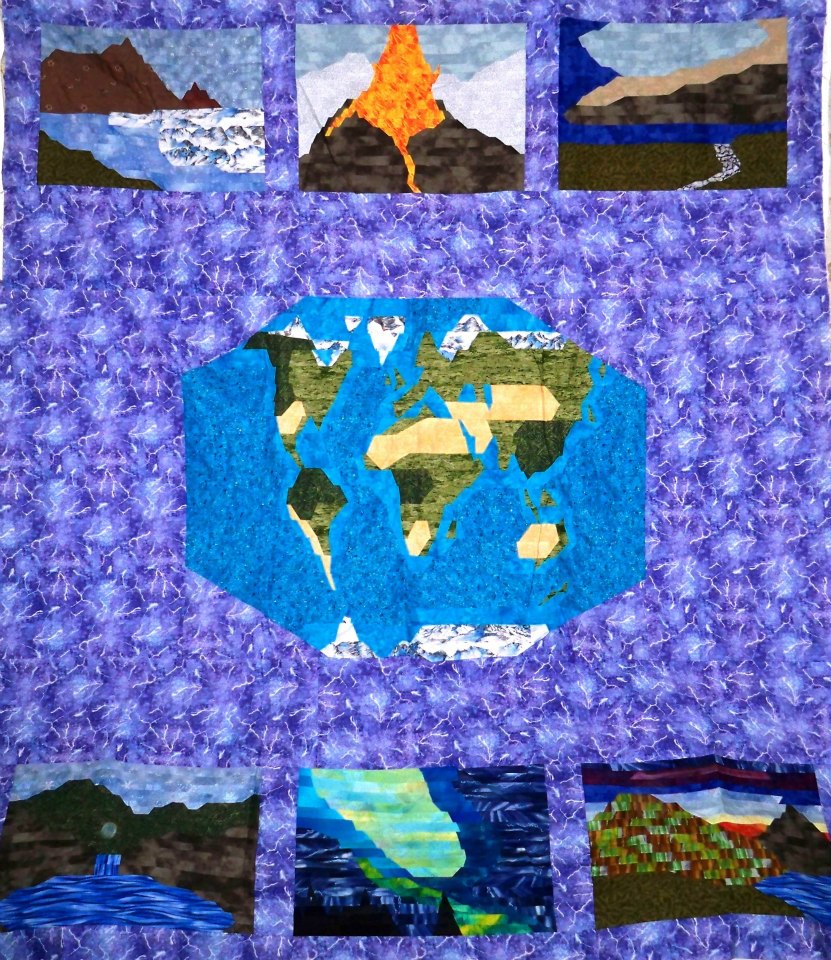 quilt that has a purple background, a map of the world with panels of volcanic eruptions, a lightning storm, glaciers and other natural phenomena.