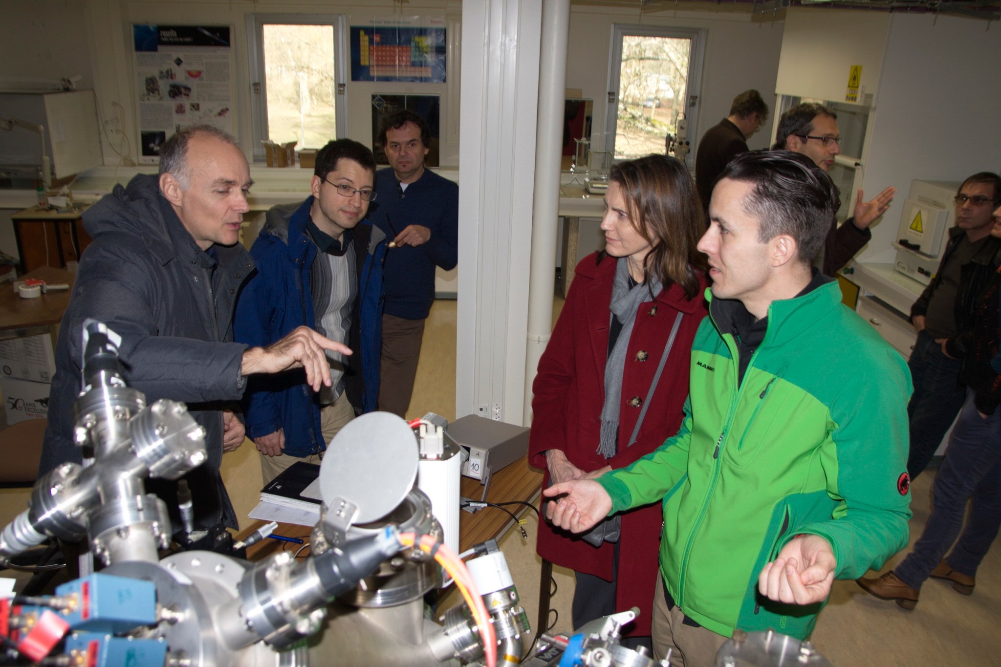 Several people stand around an instrument talking.