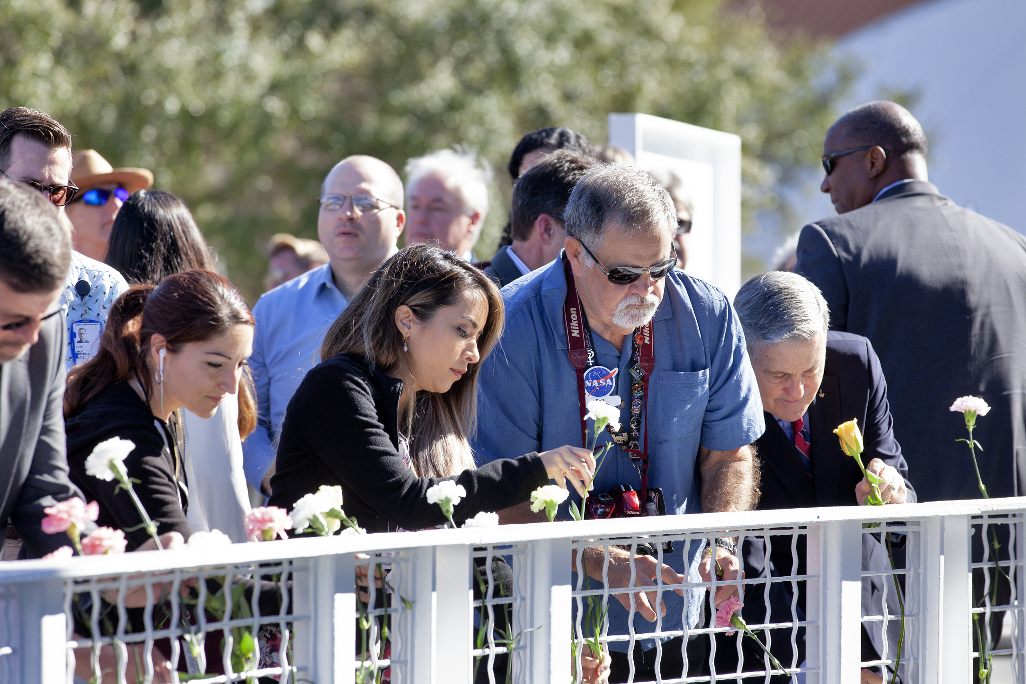 Kennedy Space Center Director Bob Cabana and guests place flowers in front of the Space Mirror Memorial 