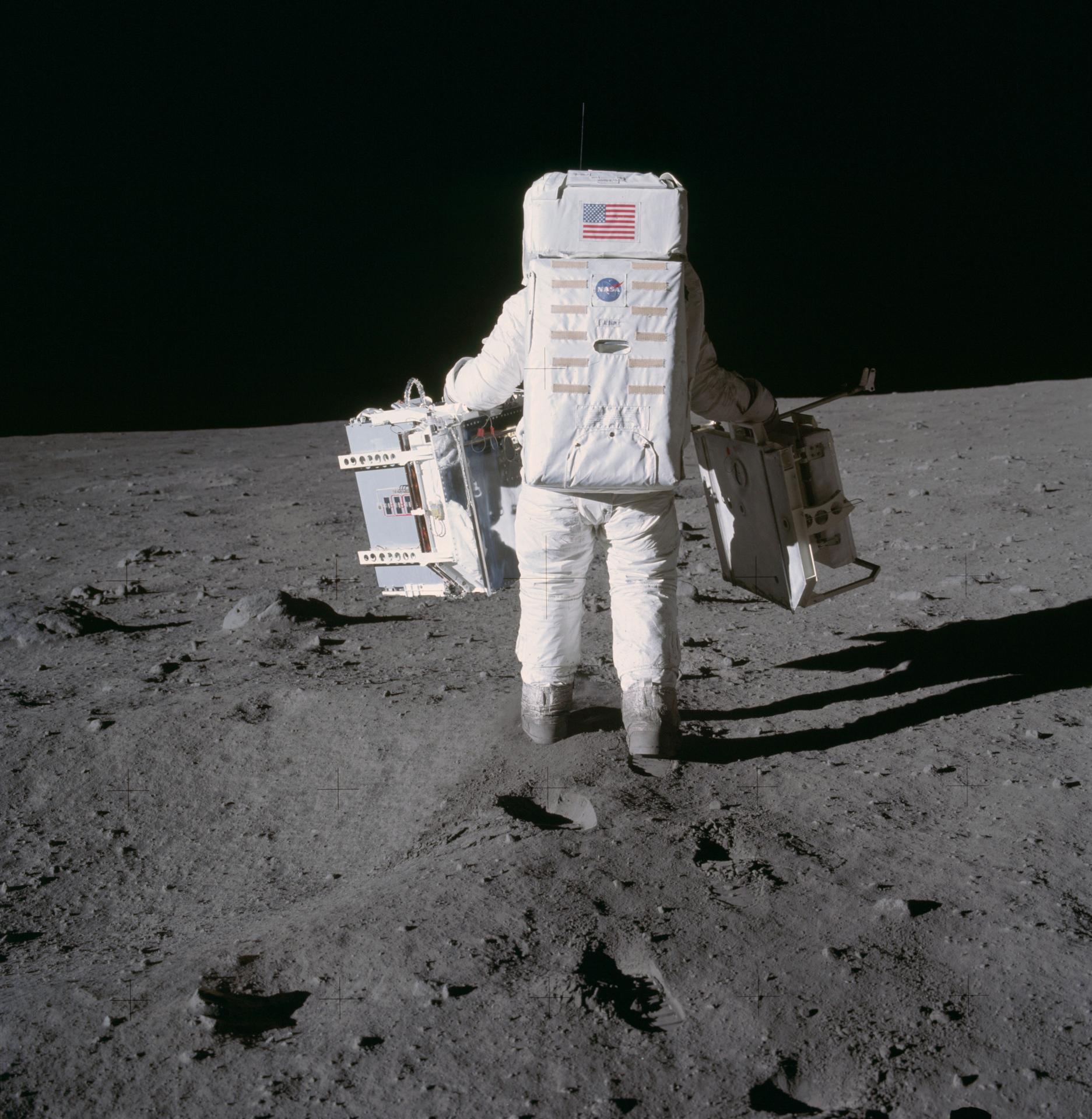Buzz Aldrin on surface of Moon with his back facing the camera. 