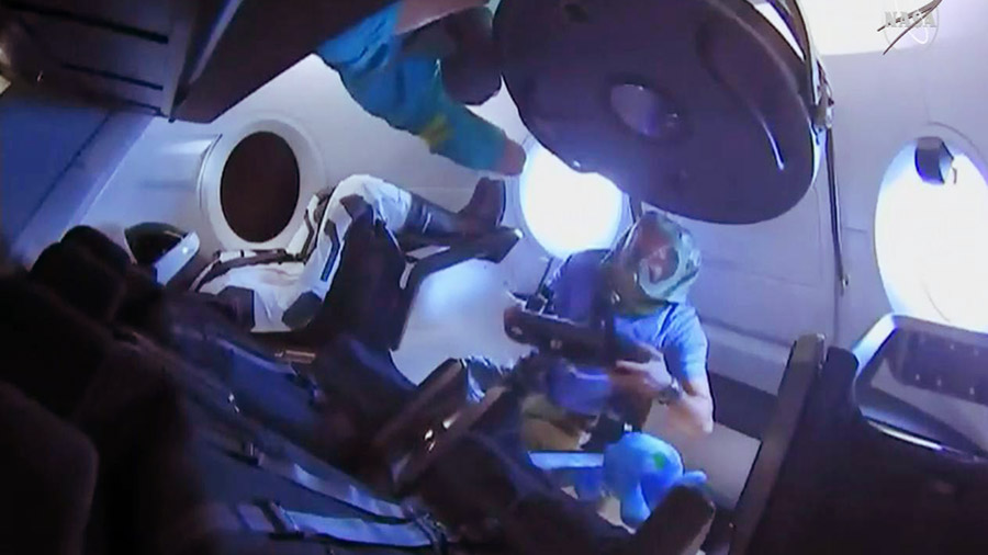 Expedition 58 crew members enter the SpaceX Crew Dragon for the first time. They are wearing protective gear to avoid breathing particulate matter that may have shaken loose during launch.